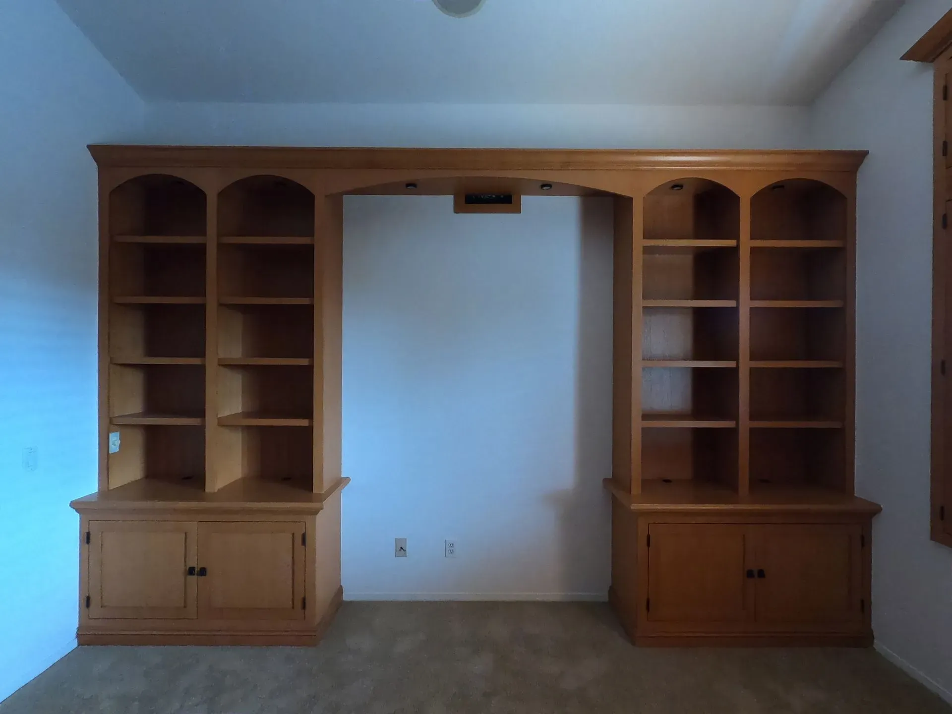 Wooden built-in wall shelves and cabinets framing a central open space in a room.