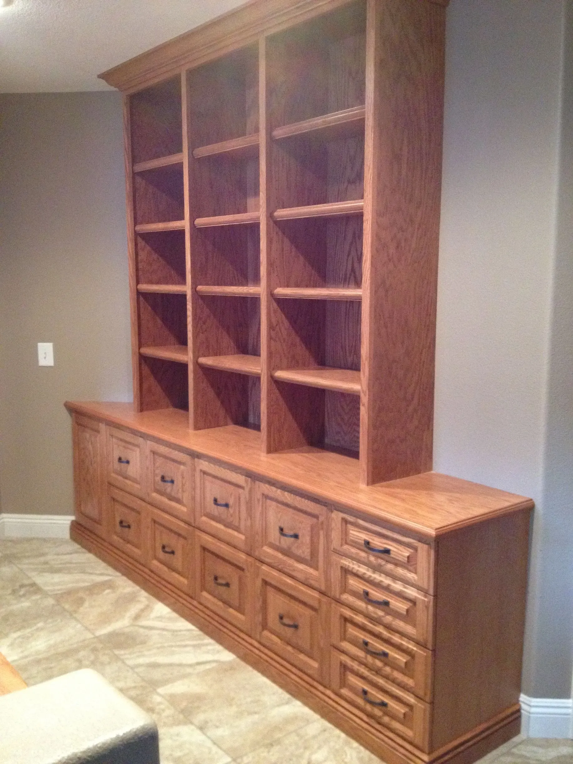 Wooden built-in bookshelf over a row of drawers against a gray wall in a room.