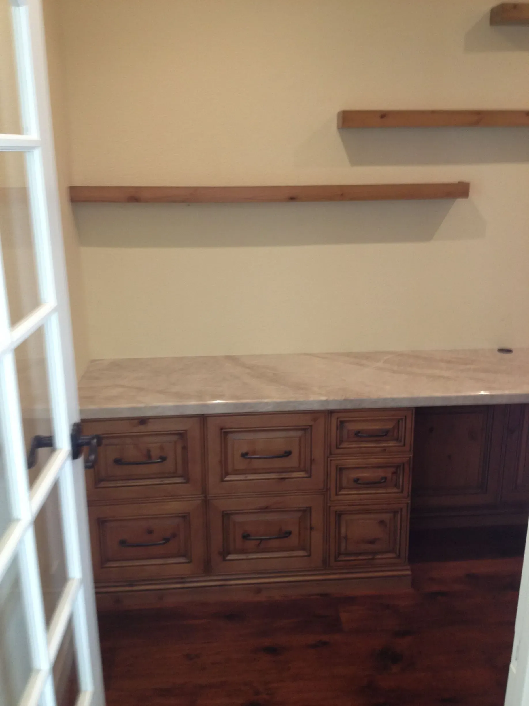 Built-in wooden cabinets with a countertop and two floating shelves in a small room