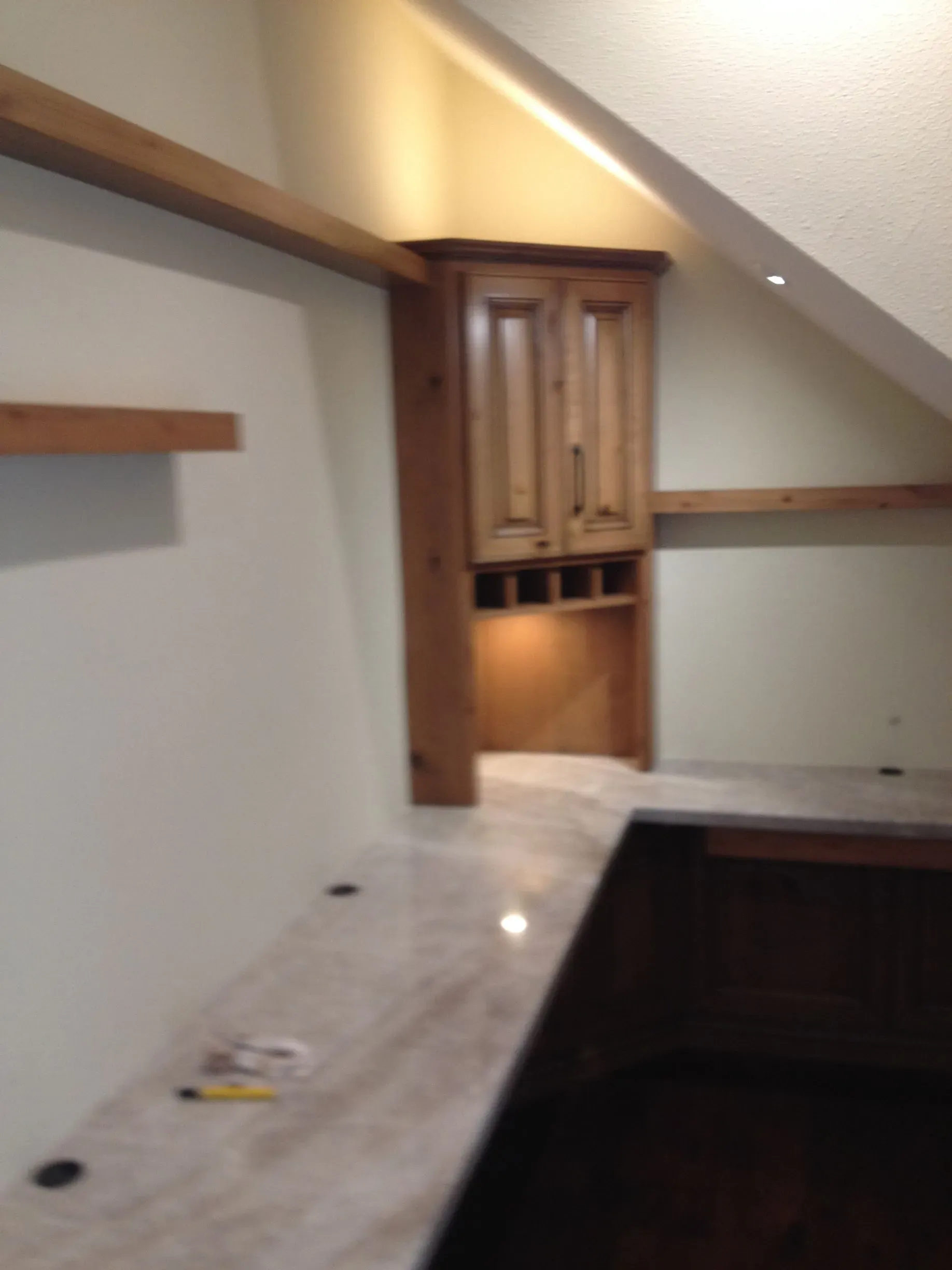 Empty kitchen corner with wood cabinets, white countertop, and slanted ceiling
