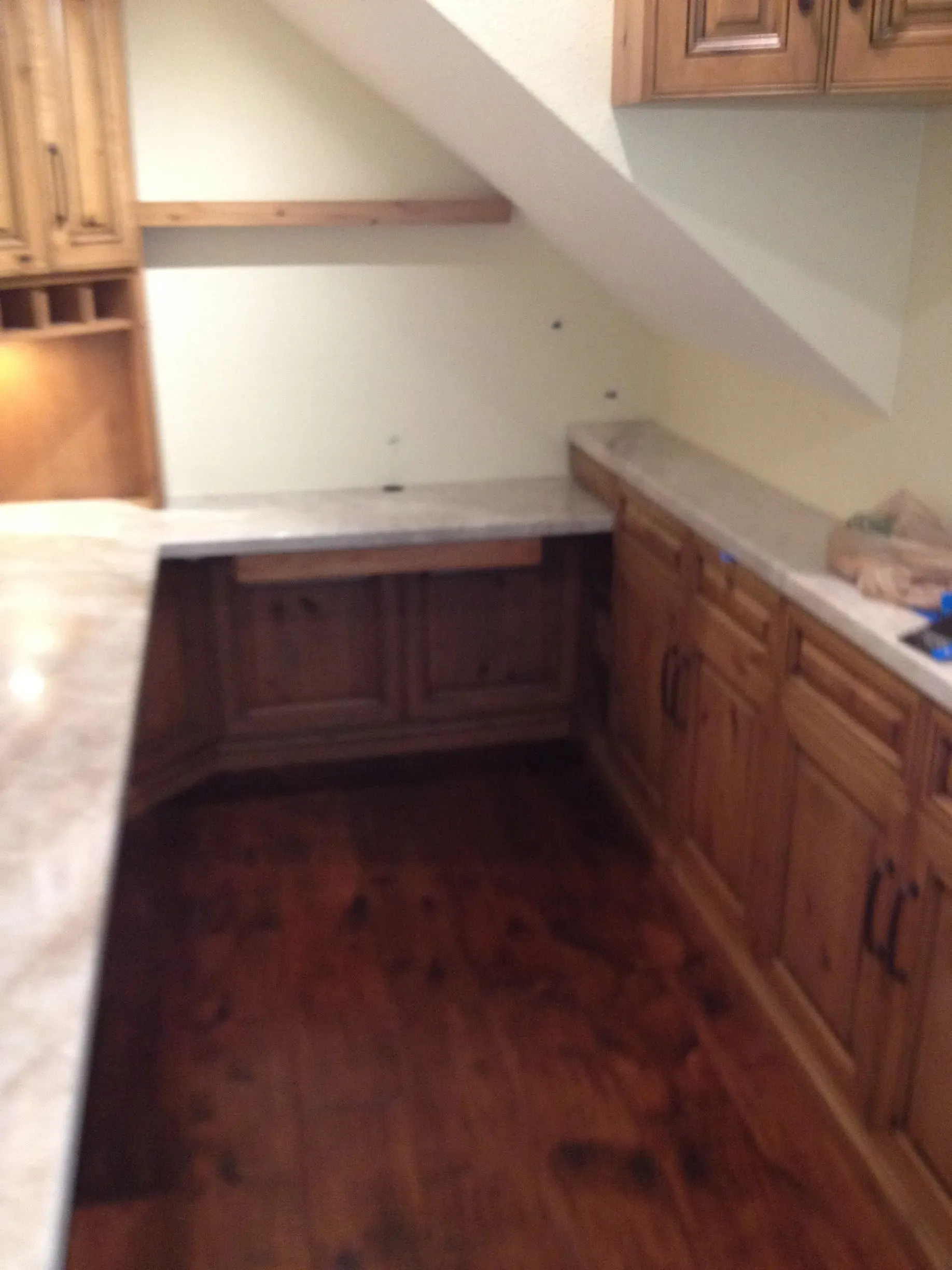 Small kitchen corner with wood cabinets, white counters, and a sloped ceiling.