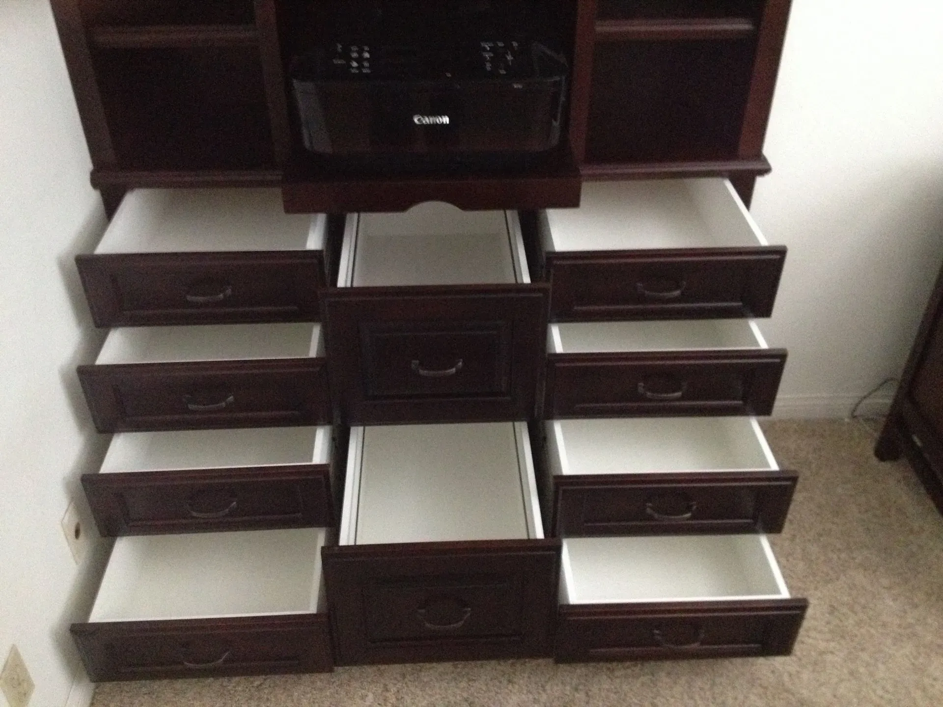 Open dresser with multiple empty drawers, dark wood and white interior shelves