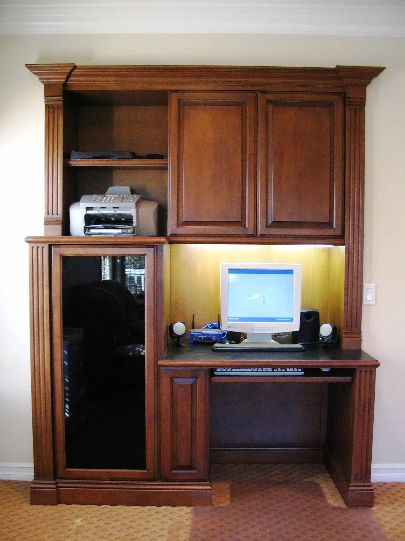 Wooden home office wall unit with computer desk, printer, and glass cabinet door