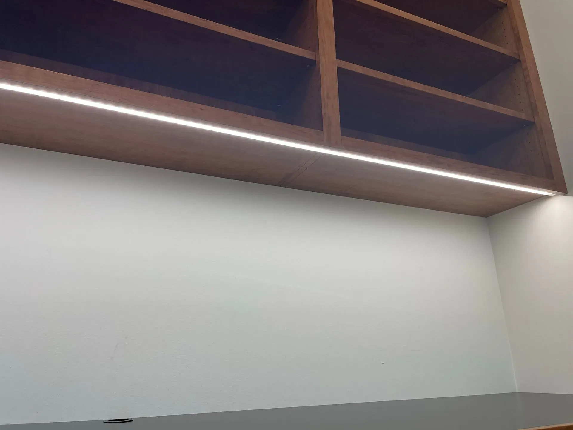 Empty room with white walls, gray lower wall, and wooden shelves above