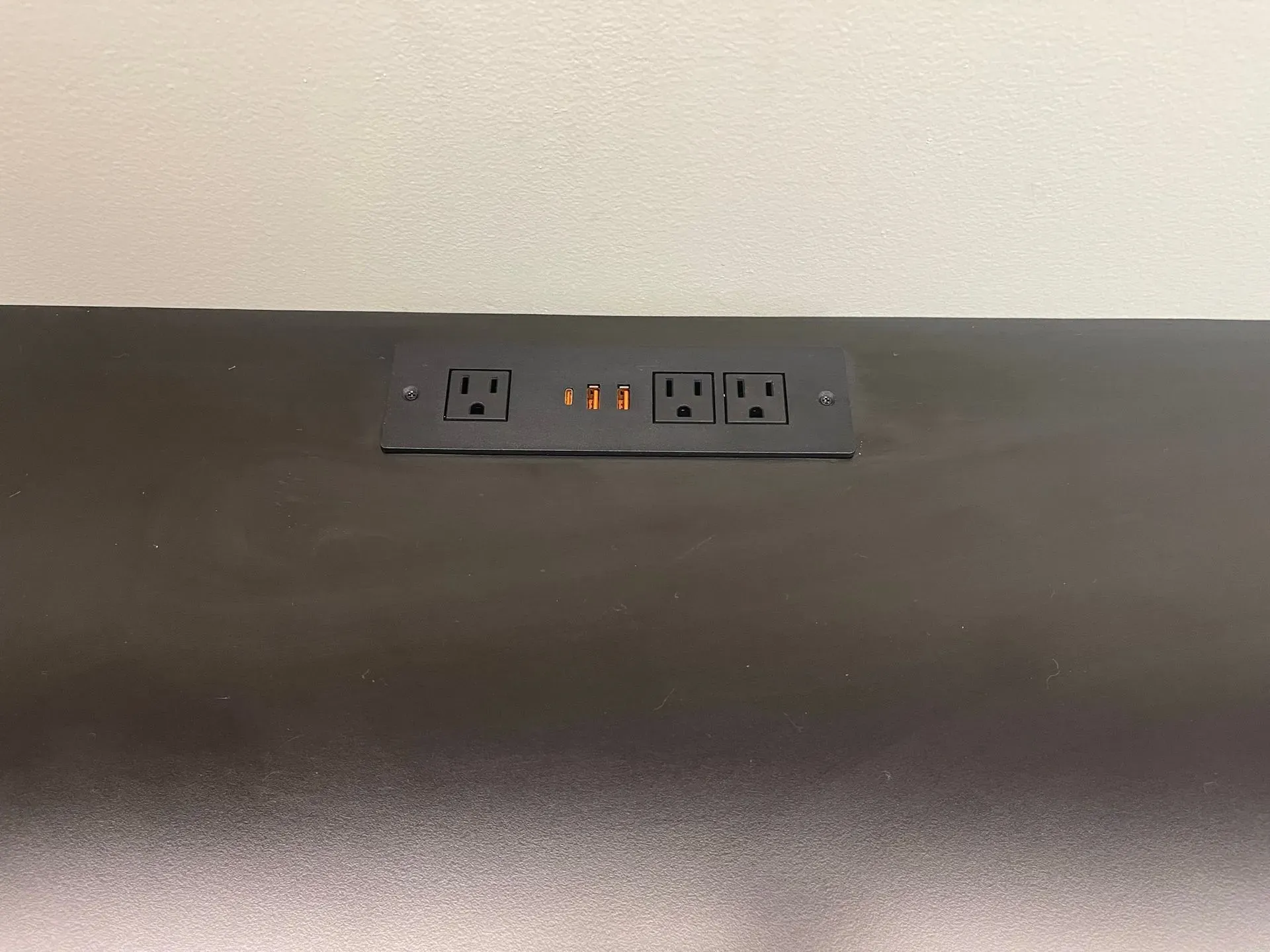 Wall outlet with USB ports on a white wall above a dark countertop