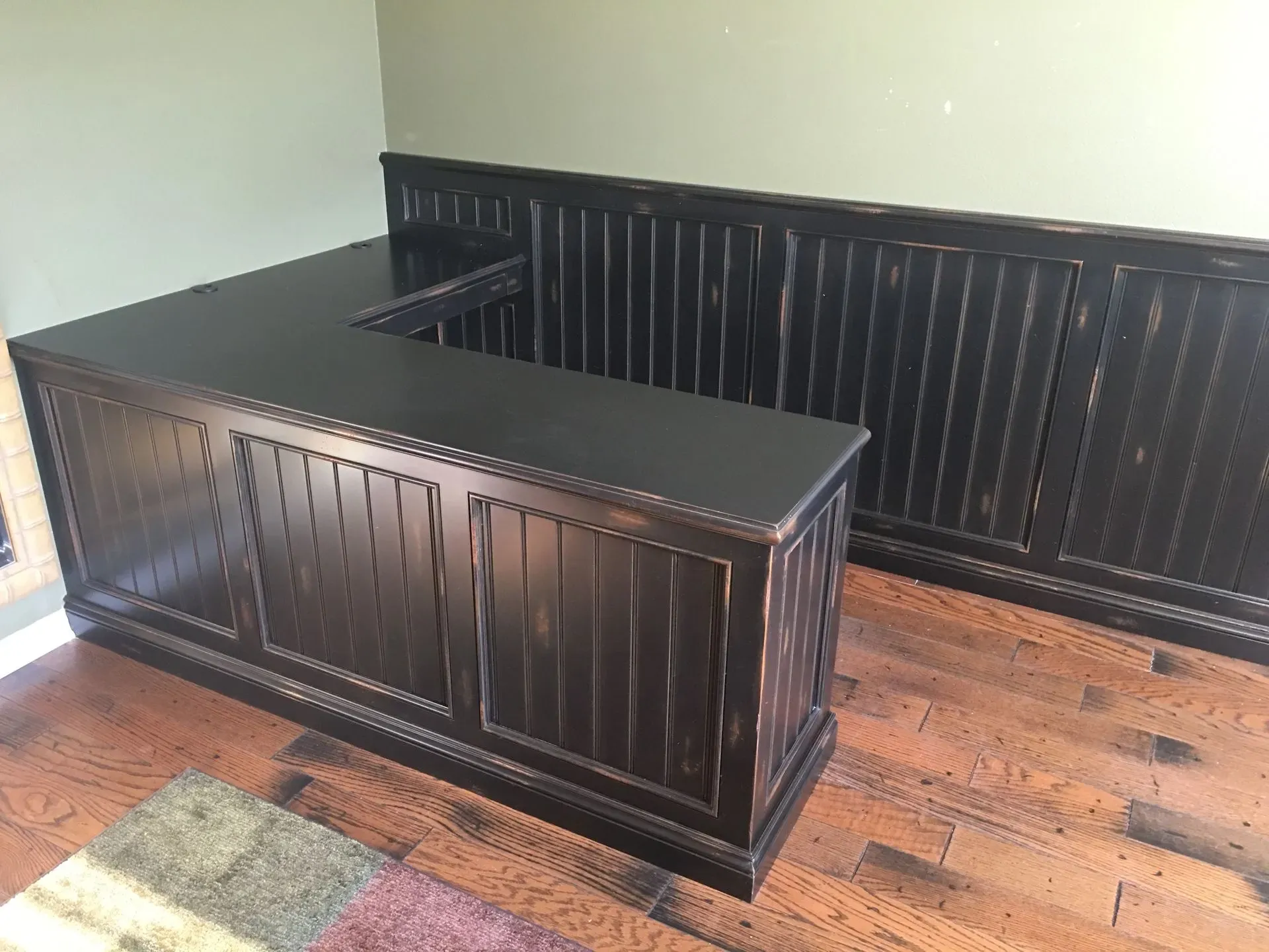Dark wood reception desk with matching wainscoting in a room with hardwood floors.