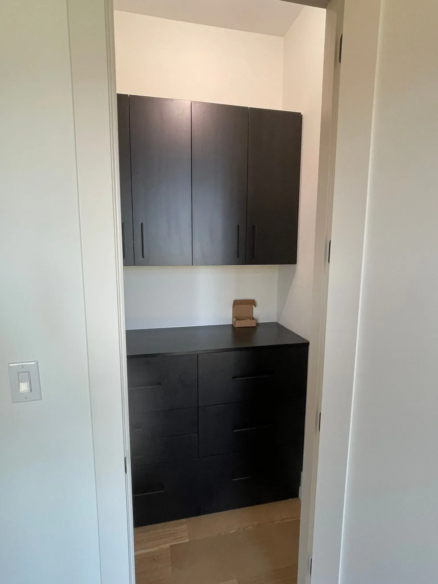 Open doorway to a small kitchen with dark cabinets and black countertops