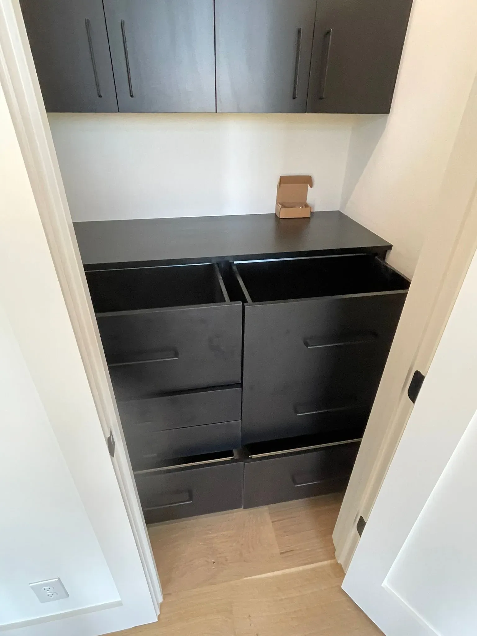 Small utility sink area with black cabinets, gray wall cabinets, and a cardboard box on the counter.