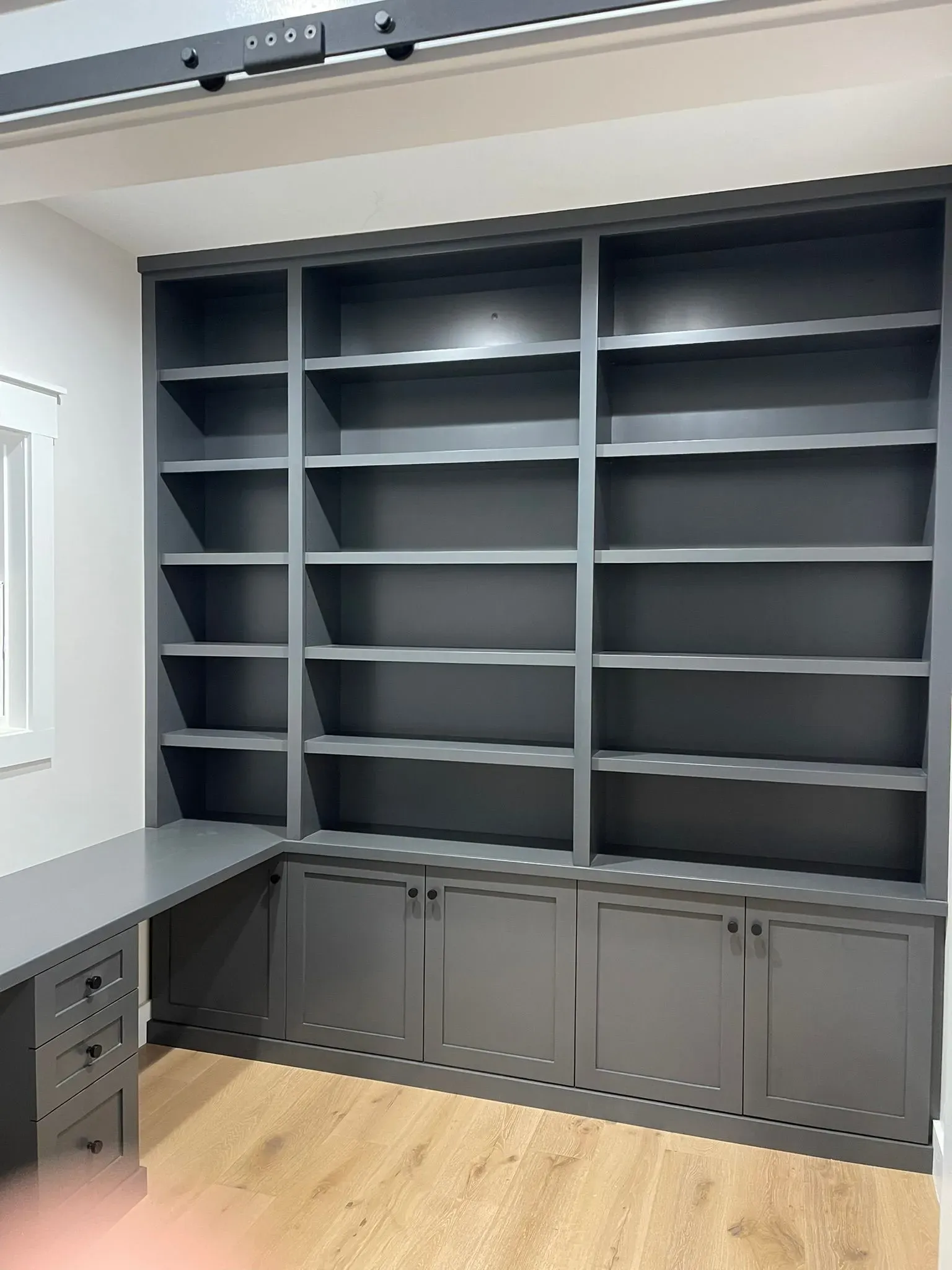 Gray built-in office shelving and cabinets along a wall, with a desk on the left.