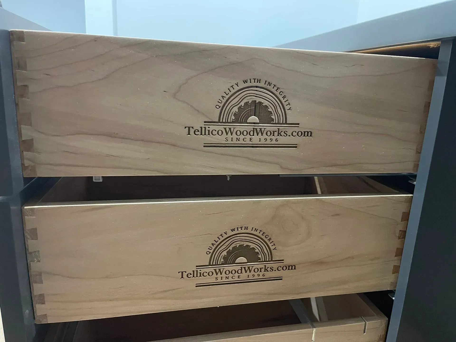 Wooden wine crate with Tellico Wine Work logo, stacked on a metal shelf.