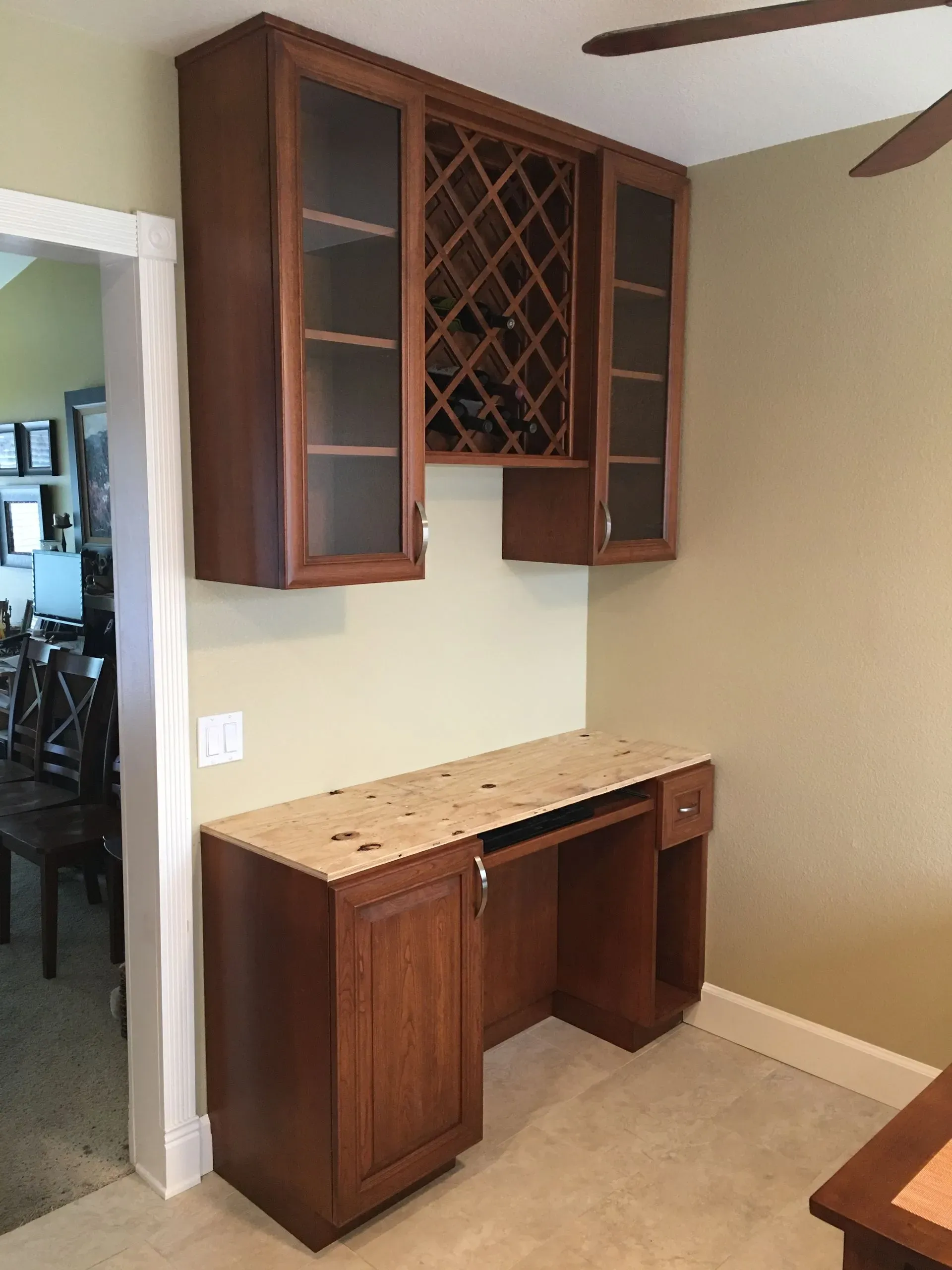 Built-in wood home bar with cabinets, wine rack, and countertop in a beige room