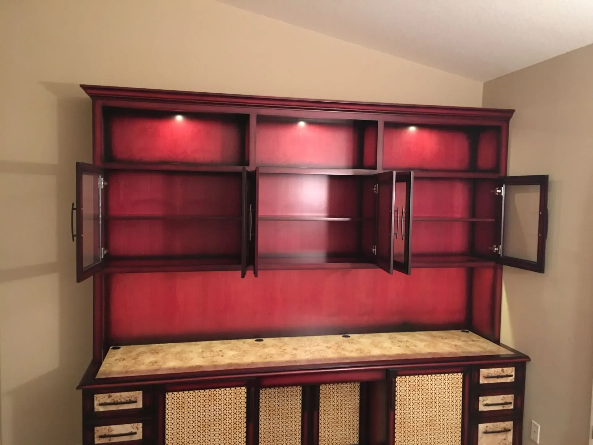 Maroon wall unit with open cabinets above a beige-topped sideboard in a room.