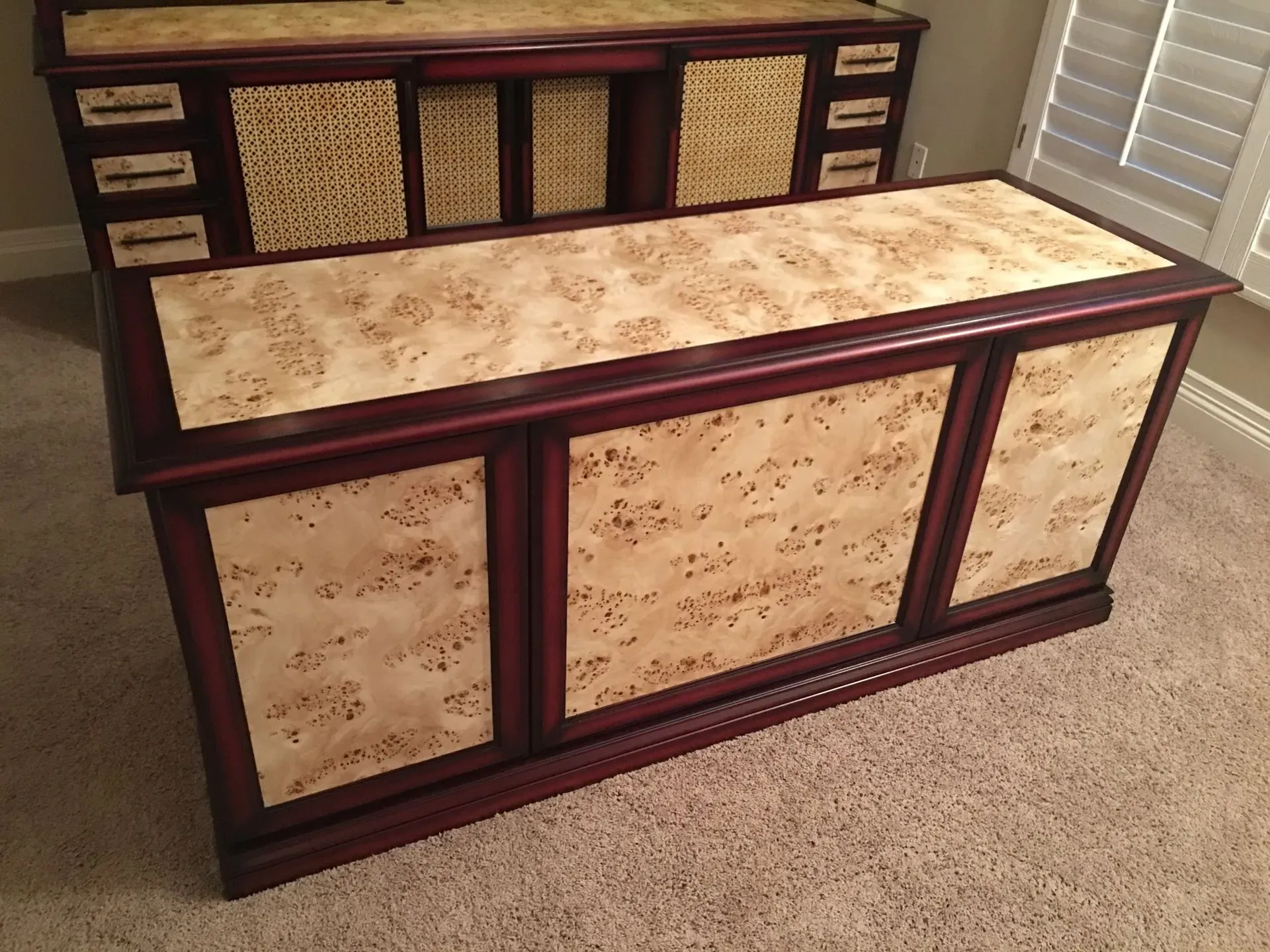 Two decorative wooden cabinets with light marbled panels and woven fronts in a room