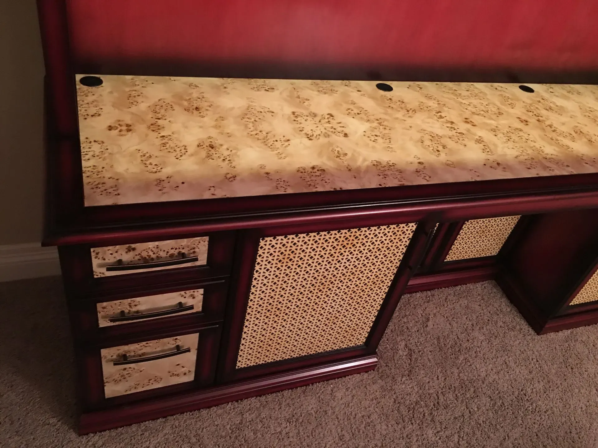 Vintage wooden cabinet with beige marbled top and woven front panels on carpet