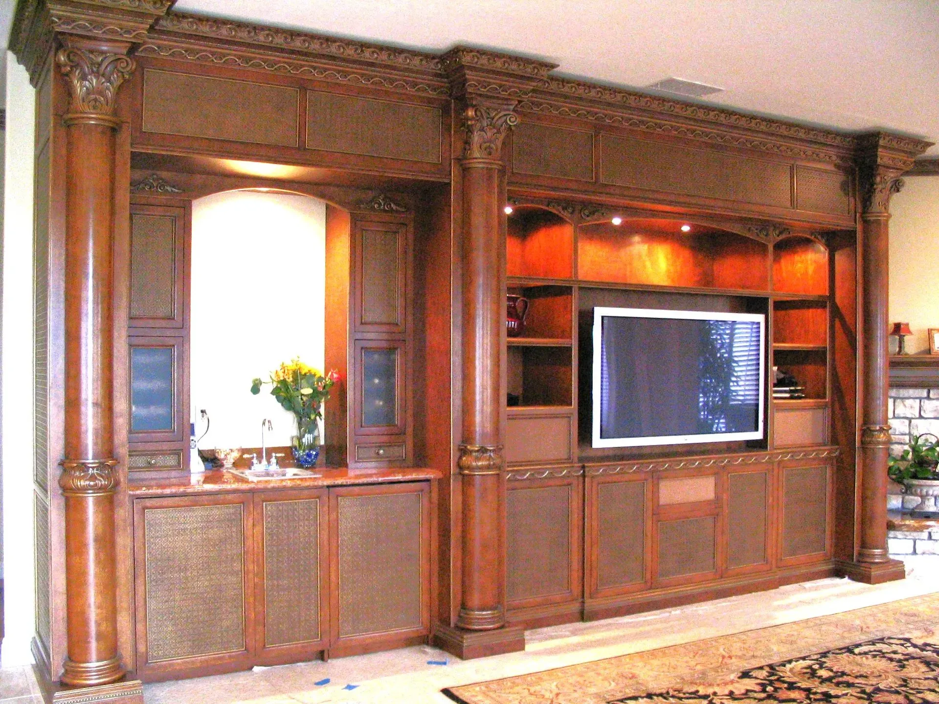 Wooden entertainment center with built-in shelving and a flat-screen TV in a living room.