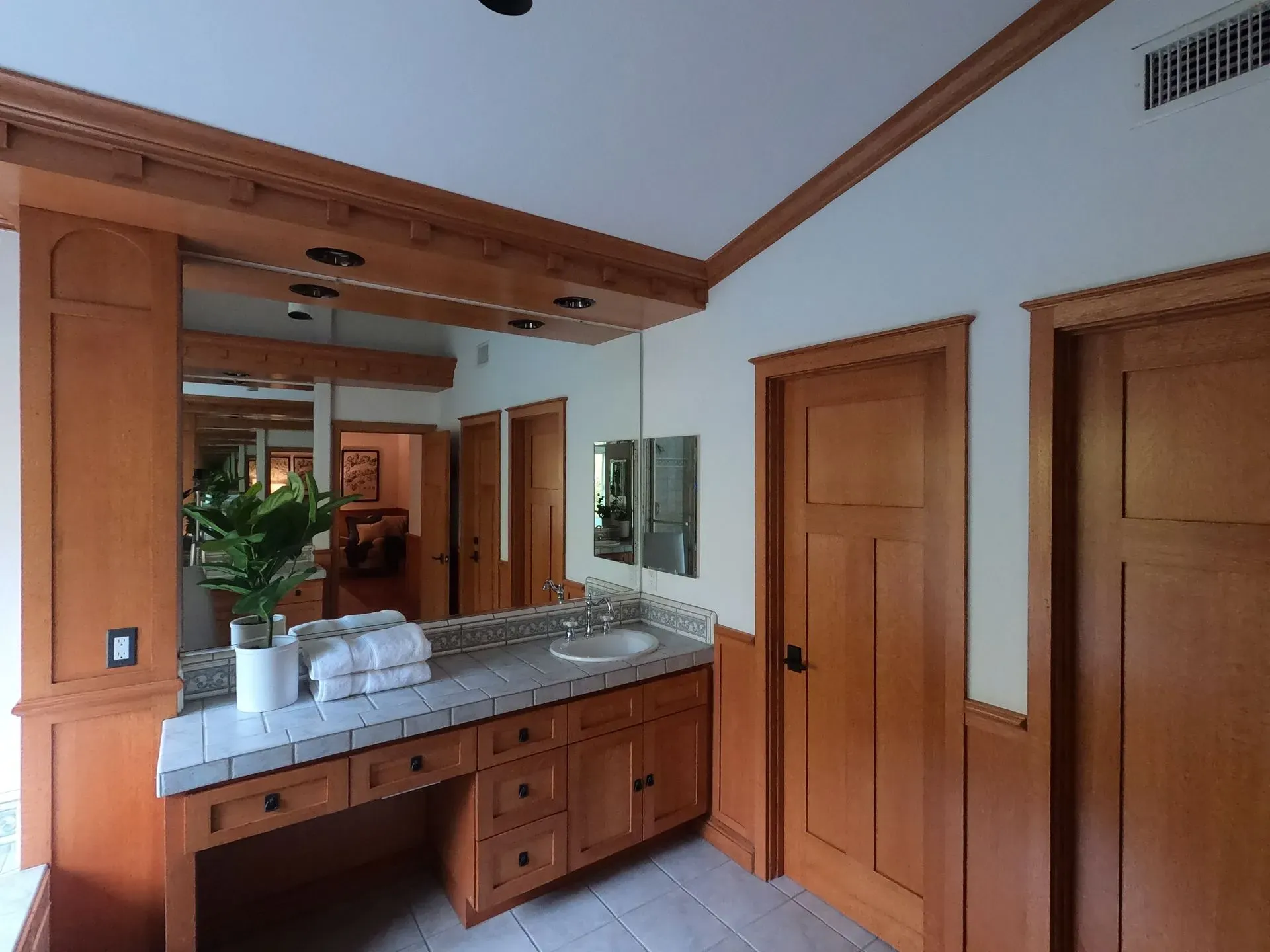 Wood-paneled bathroom with a large mirror, double vanity, and closed wooden doors
