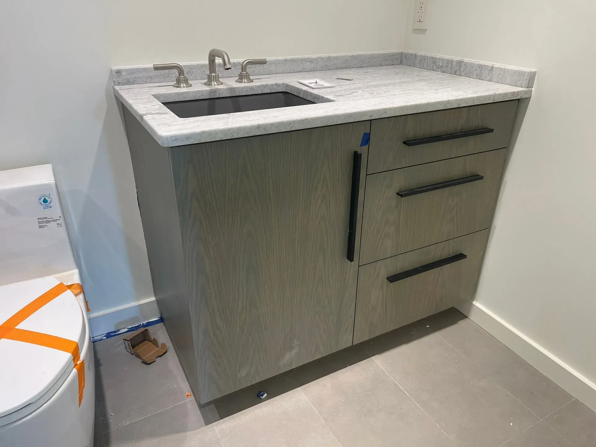 Gray vanity sink cabinet with chrome faucet in a small bathroom