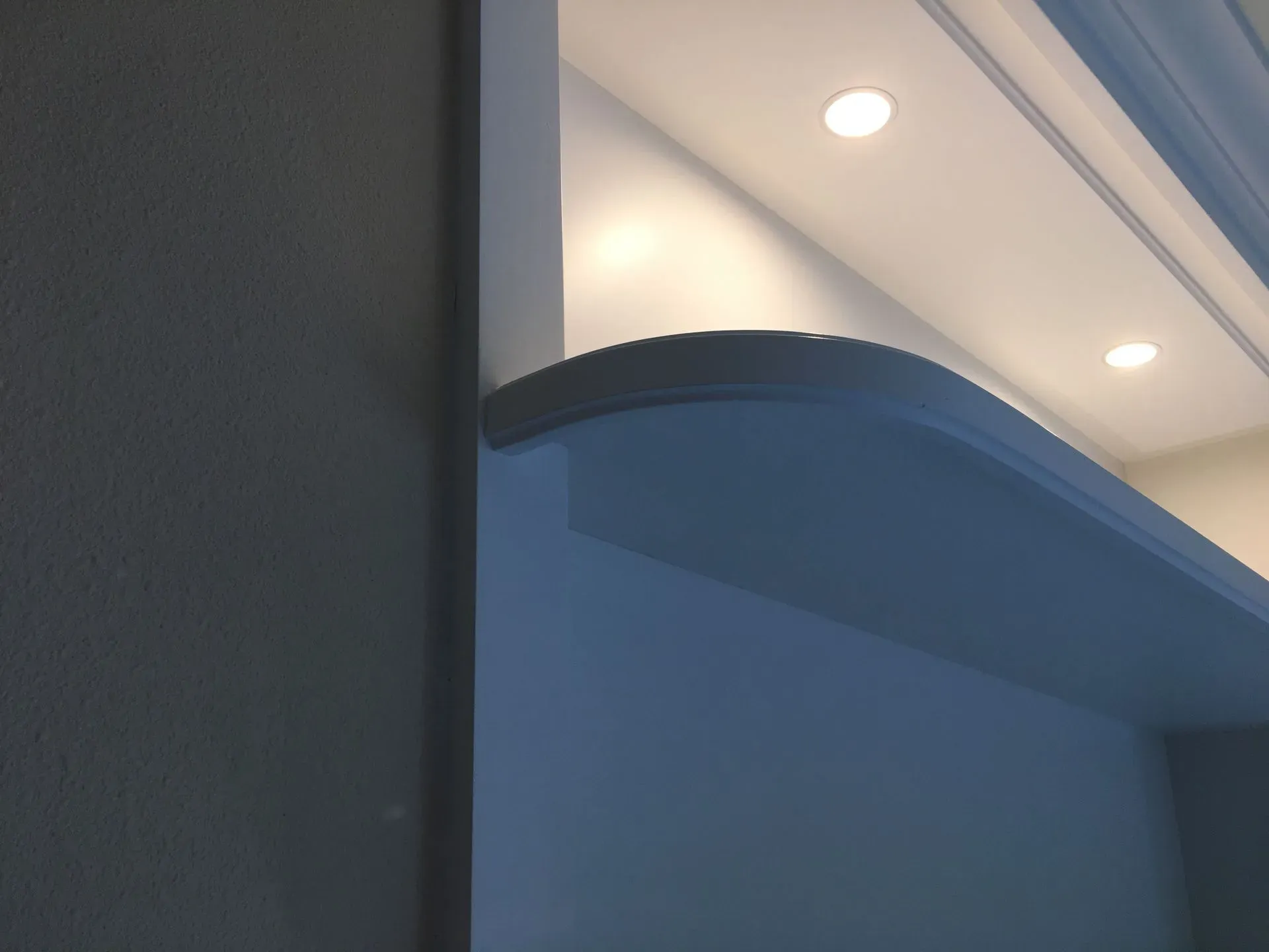 Close-up of a blue wall and ceiling with recessed lights in a modern interior.