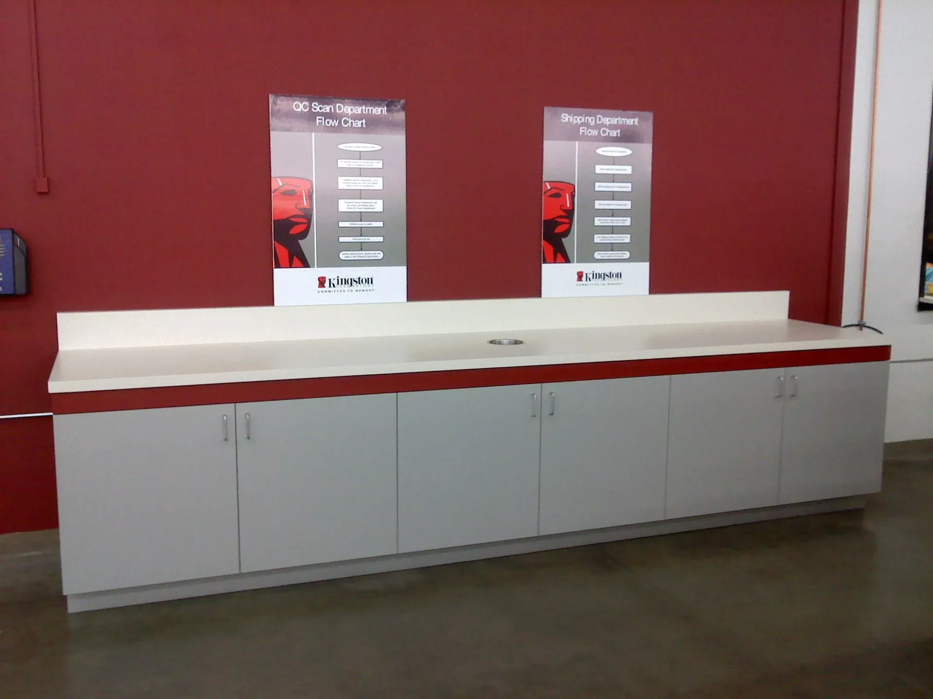 Empty white service counter against a red wall with two posters above it