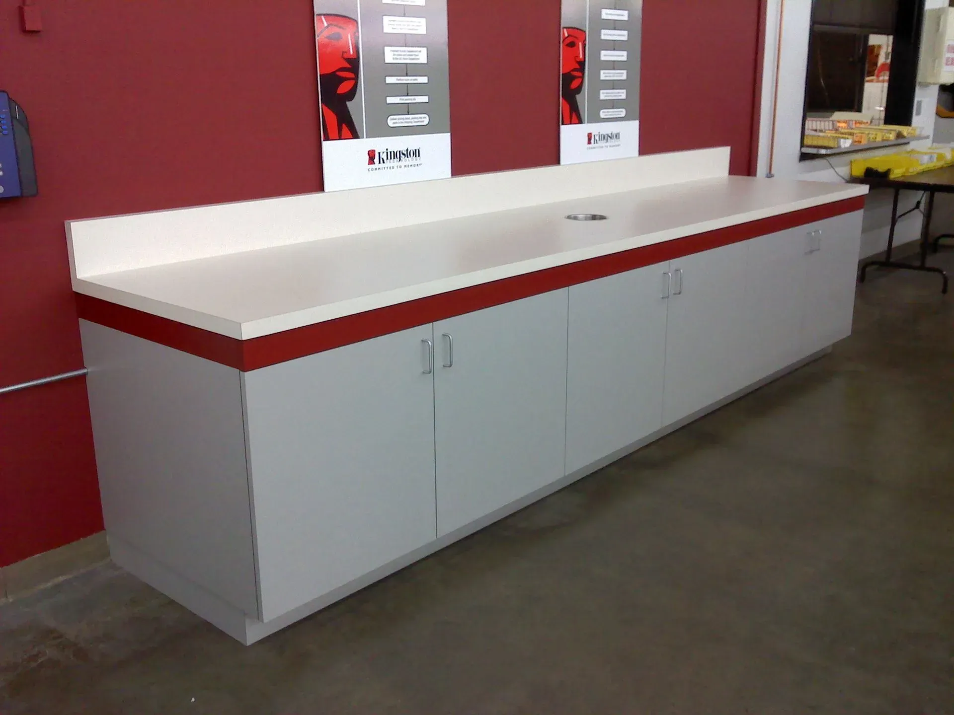 White counter with red trim in an empty room with red walls and concrete floor