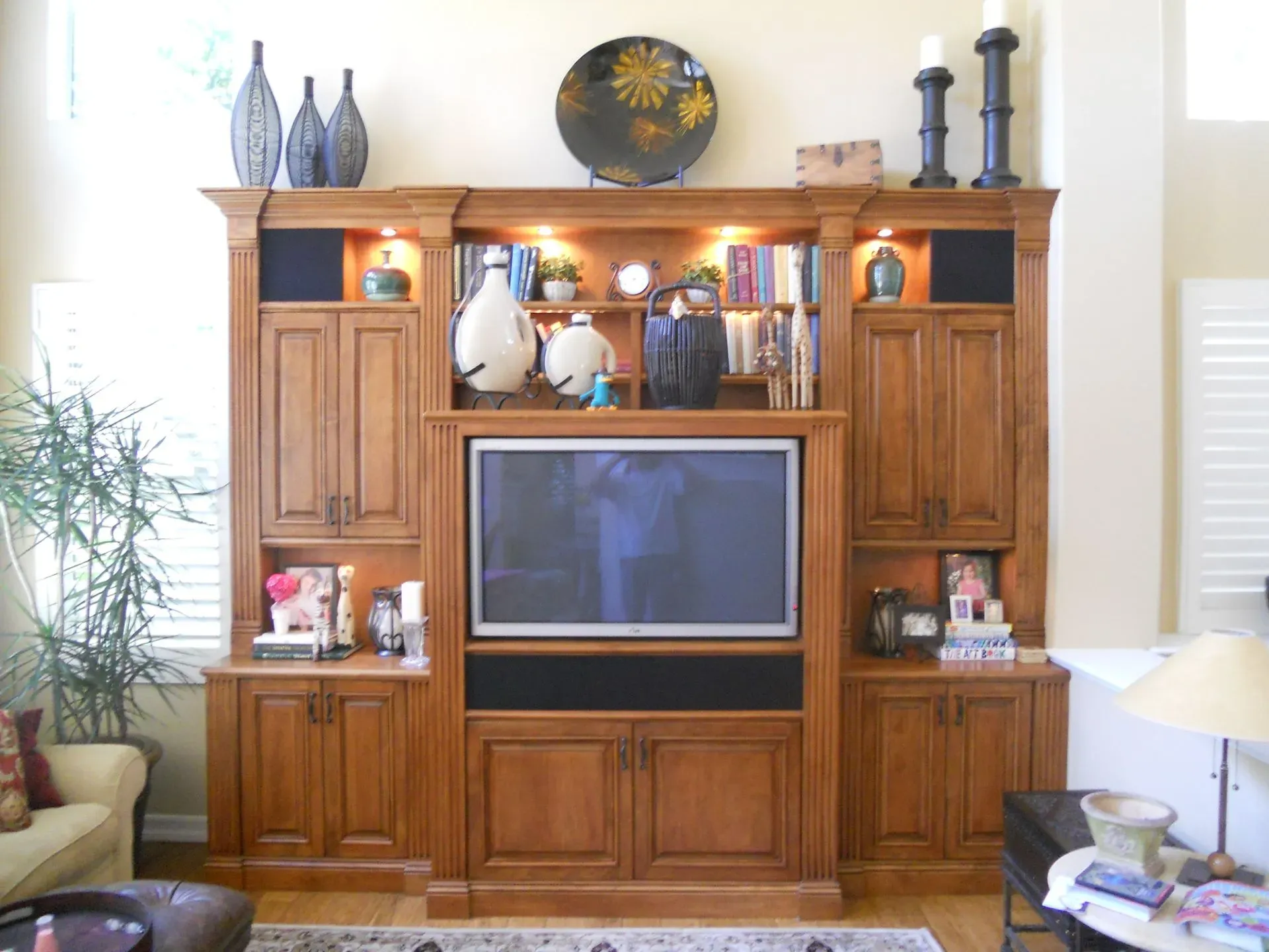Wooden entertainment center with TV, decorative vases, and lamps in a bright living room