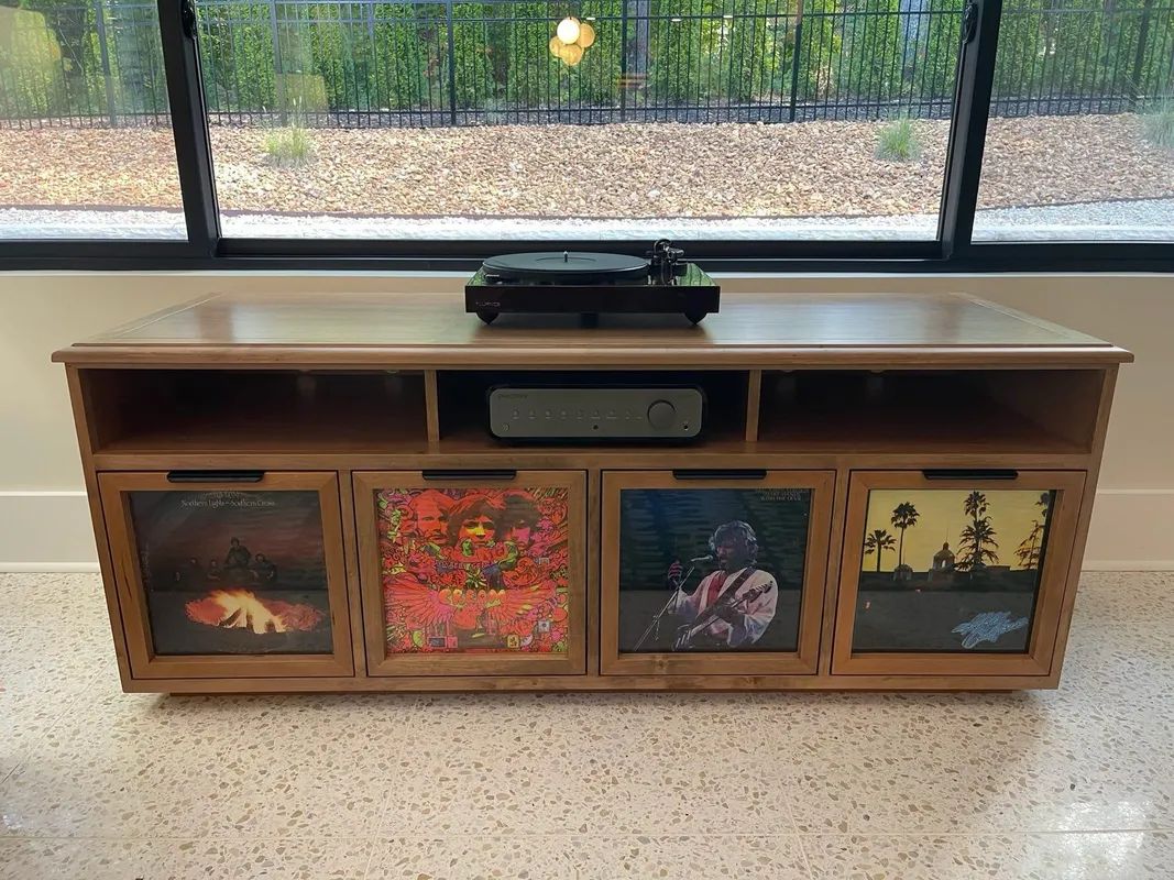 Wooden cabinet with colorful art panels in front of a windowed indoor space