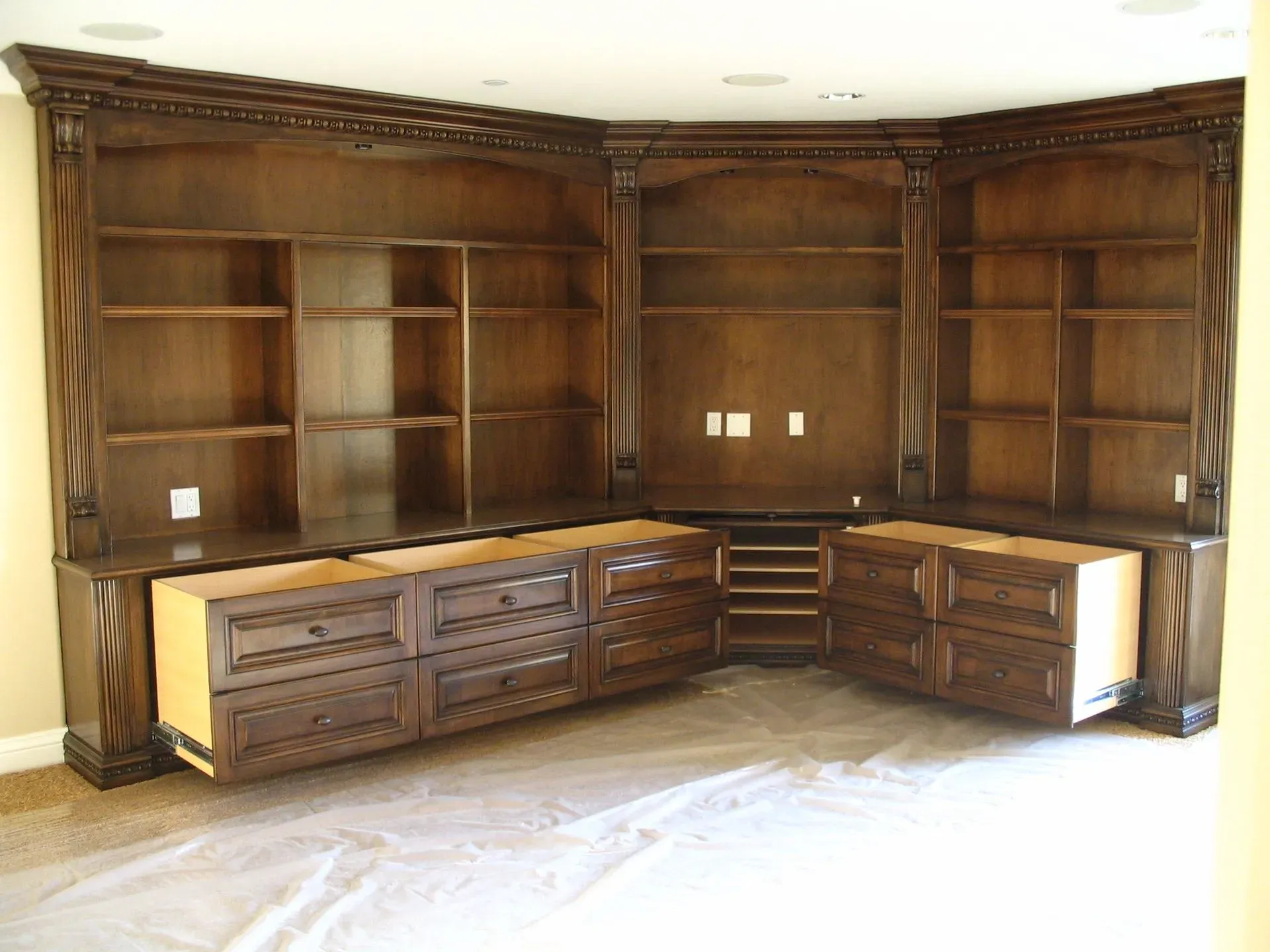 Built-in dark wood cabinetry and bookshelves in a room, with cabinets along two walls and a center bay.