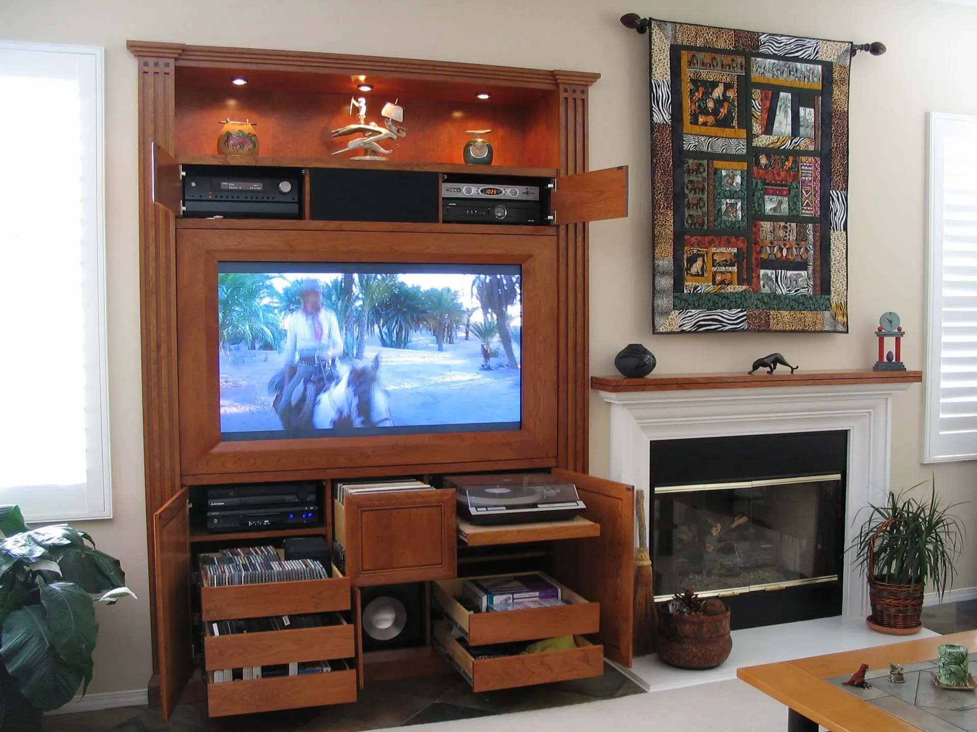 Living room with wooden entertainment center, TV, fireplace, and colorful wall art