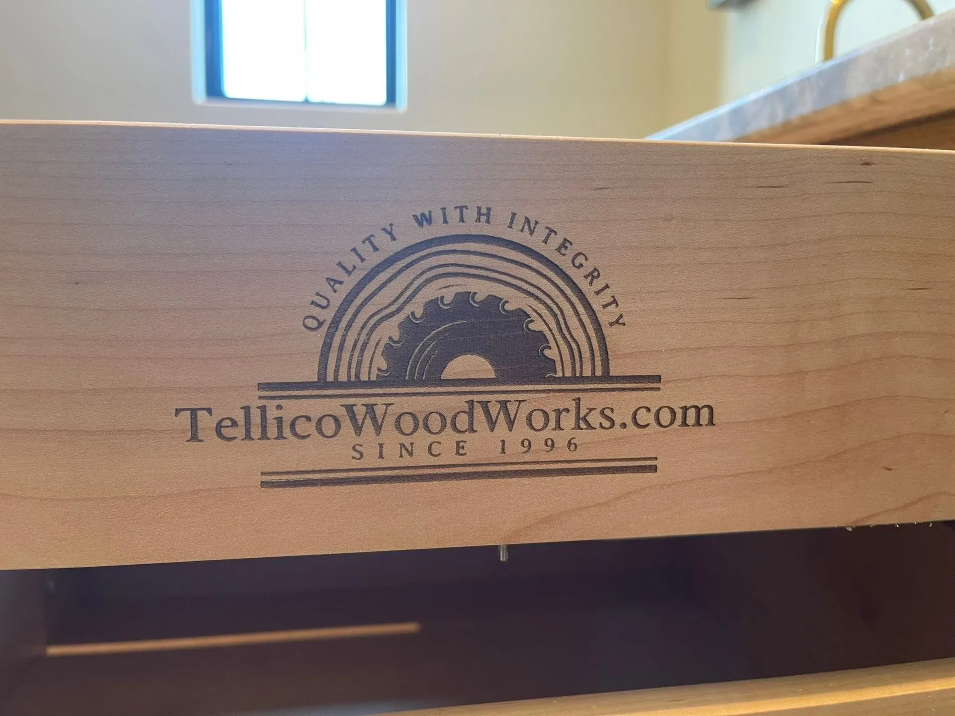 Laser-engraved TellicoWoodWorks.com logo on a light wood board, with “Quality with Integrity” and “Since 2014” text