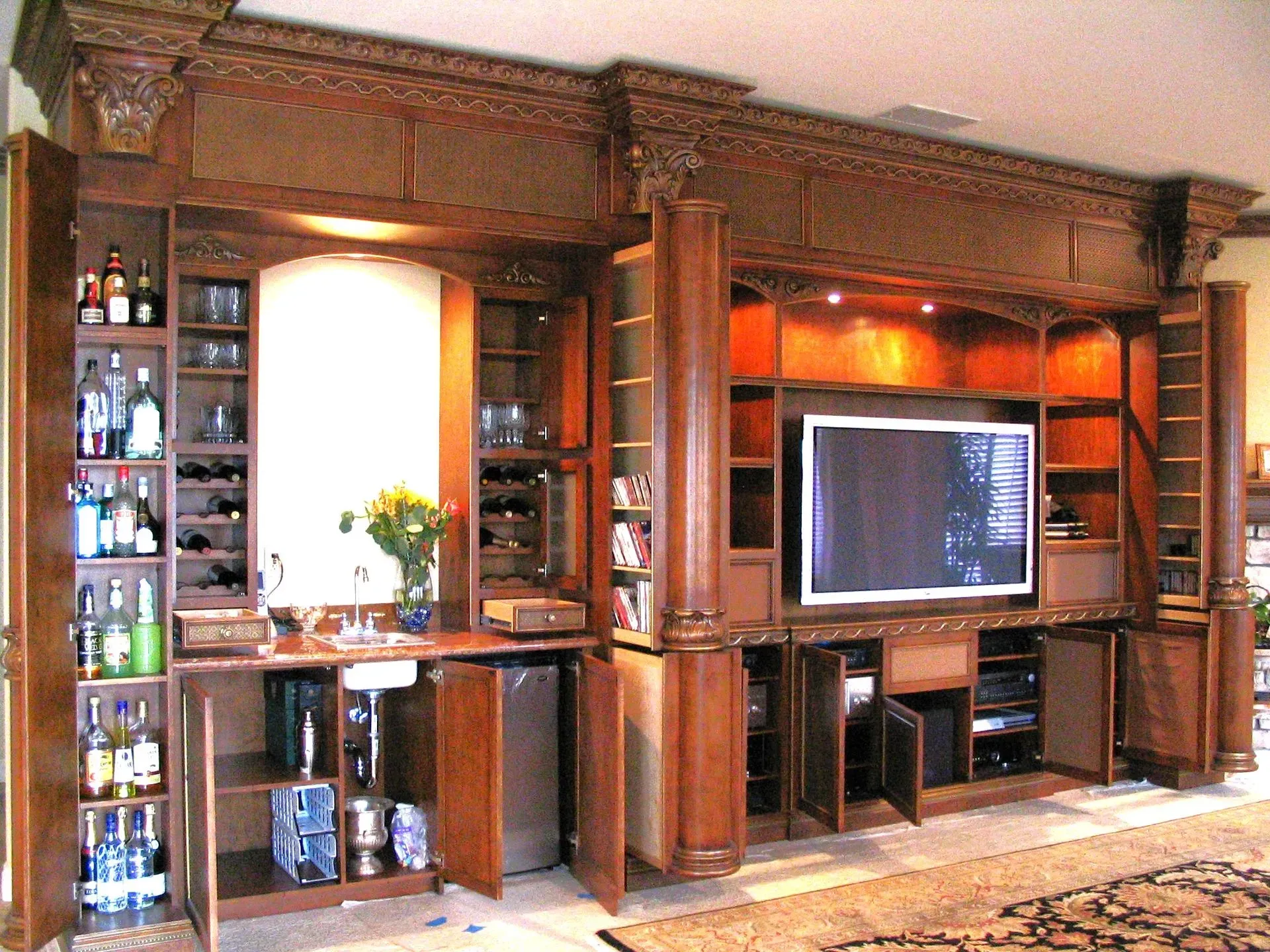 Wood-paneled living room wall with built-in shelves, cabinets, and a mounted flat-screen TV