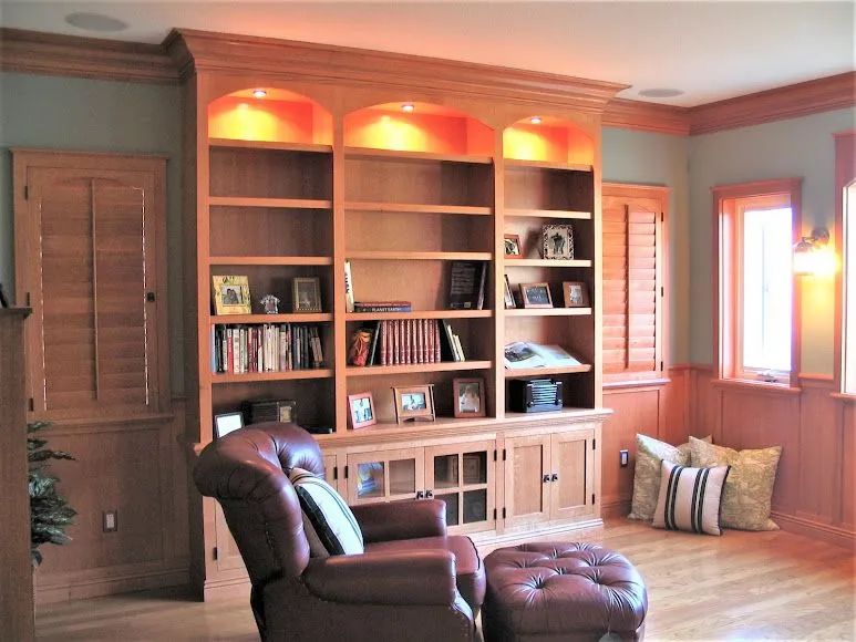 Cozy living room with built-in bookshelves, leather chair, ottoman, and warm recessed lighting