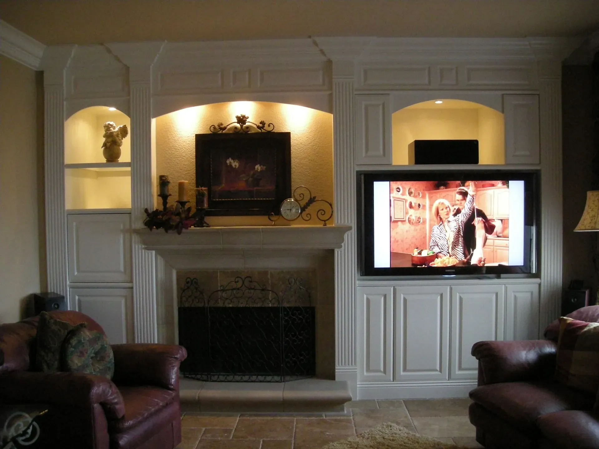 Living room with white built-ins, fireplace, and a TV showing a person in a bright scene