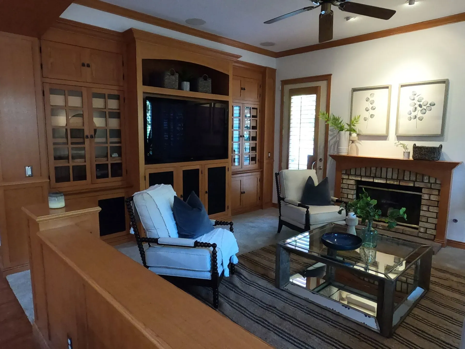 Cozy living room with wood built-ins, fireplace, glass coffee table, and blue armchairs