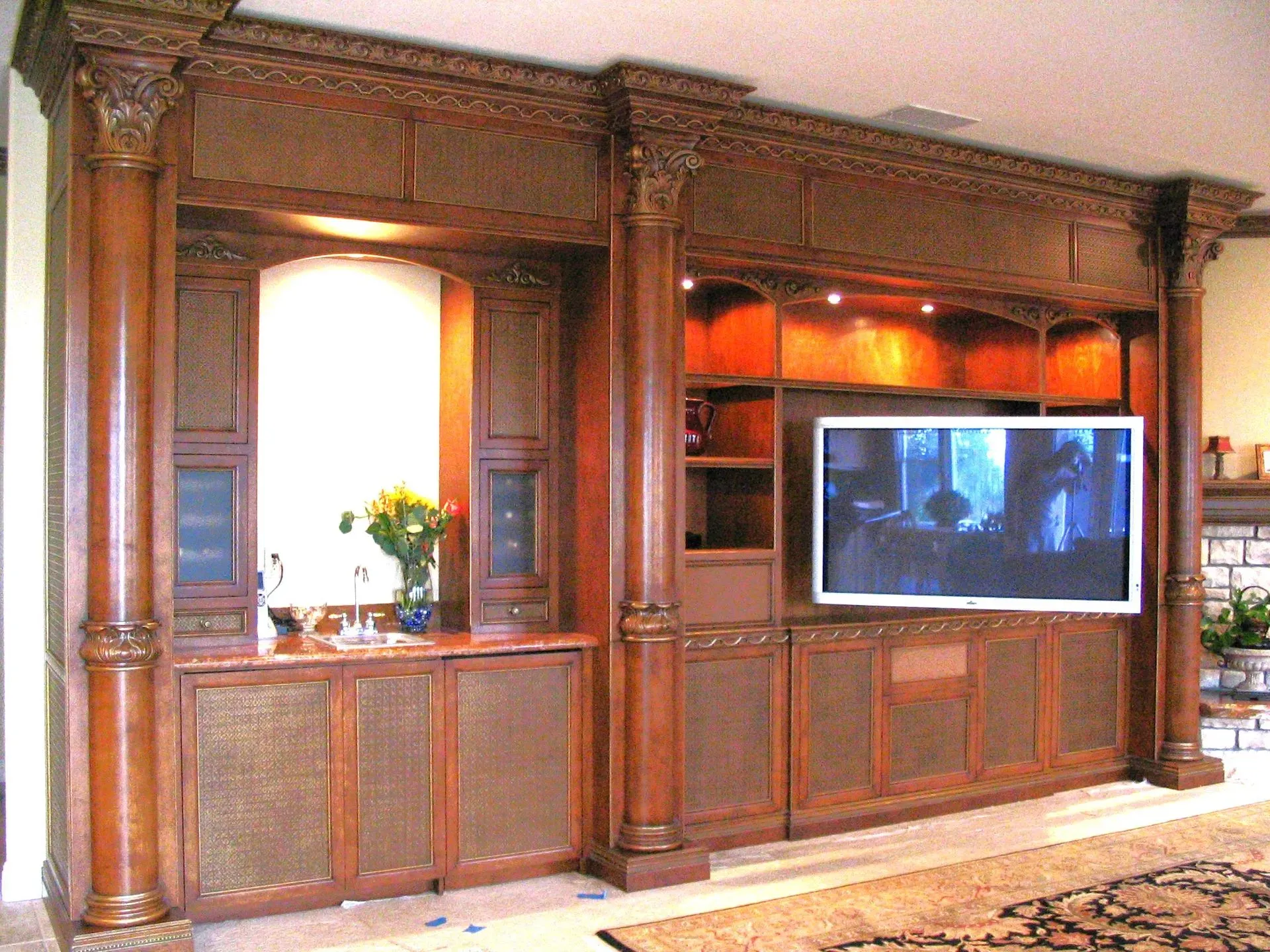 Large wooden entertainment wall unit with shelves, a TV, and a decorative niche in a living room