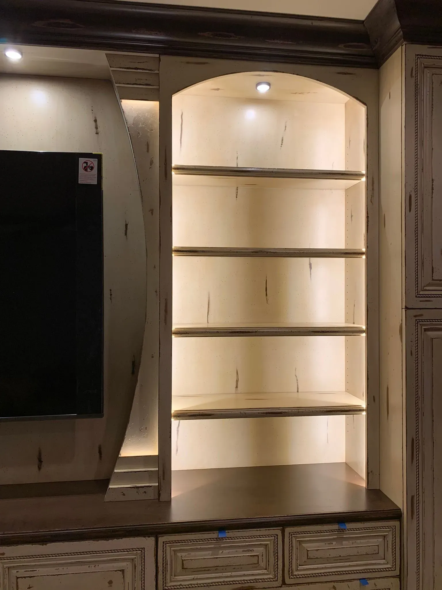 Built-in white shelving alcove with curved shelves and drawers in a room