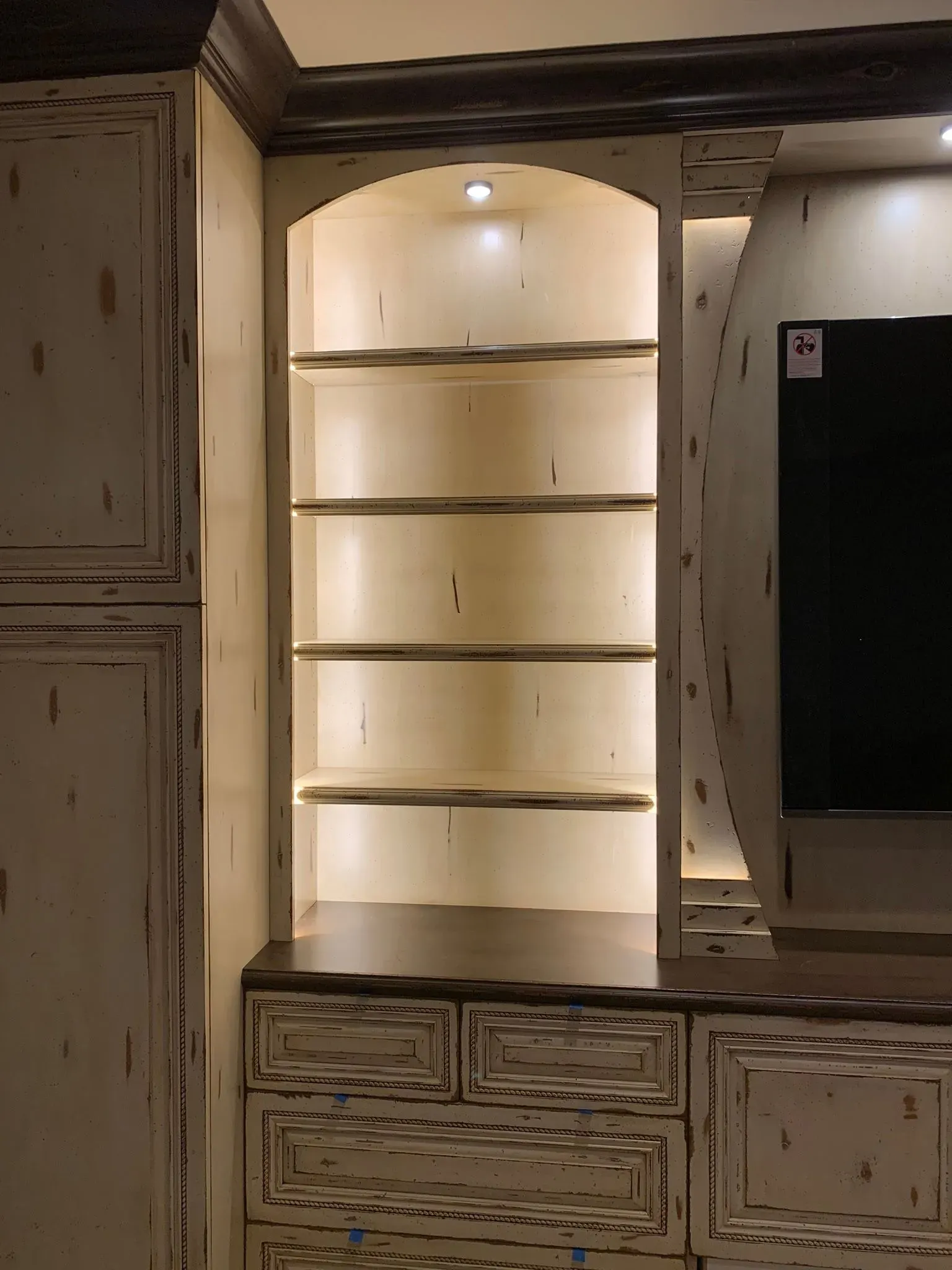 Built-in illuminated shelves with cabinets in a hallway alcove
