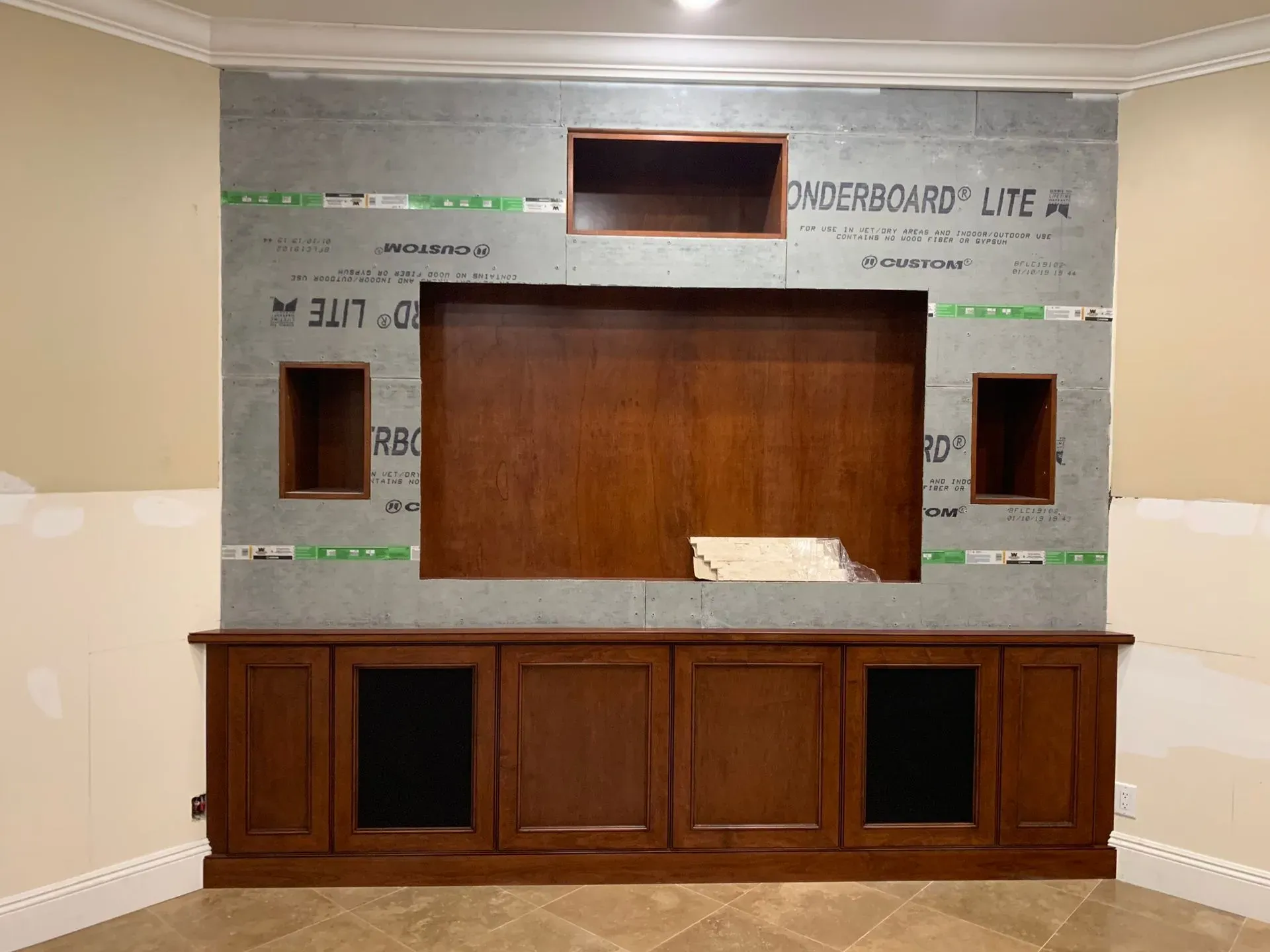 Wood-paneled reception desk under construction with unfinished wall and framing materials behind it
