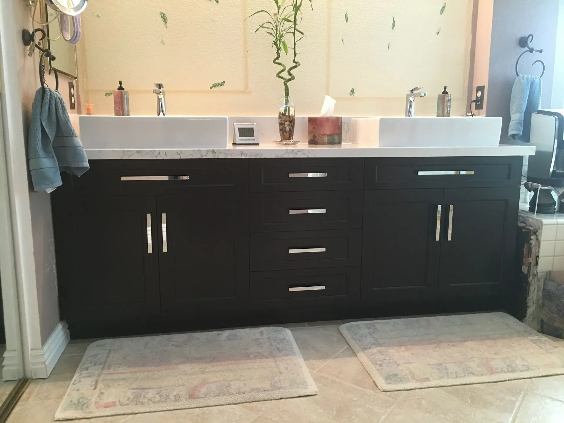 Modern bathroom vanity with double sinks, black cabinets, and towels hanging on either side.