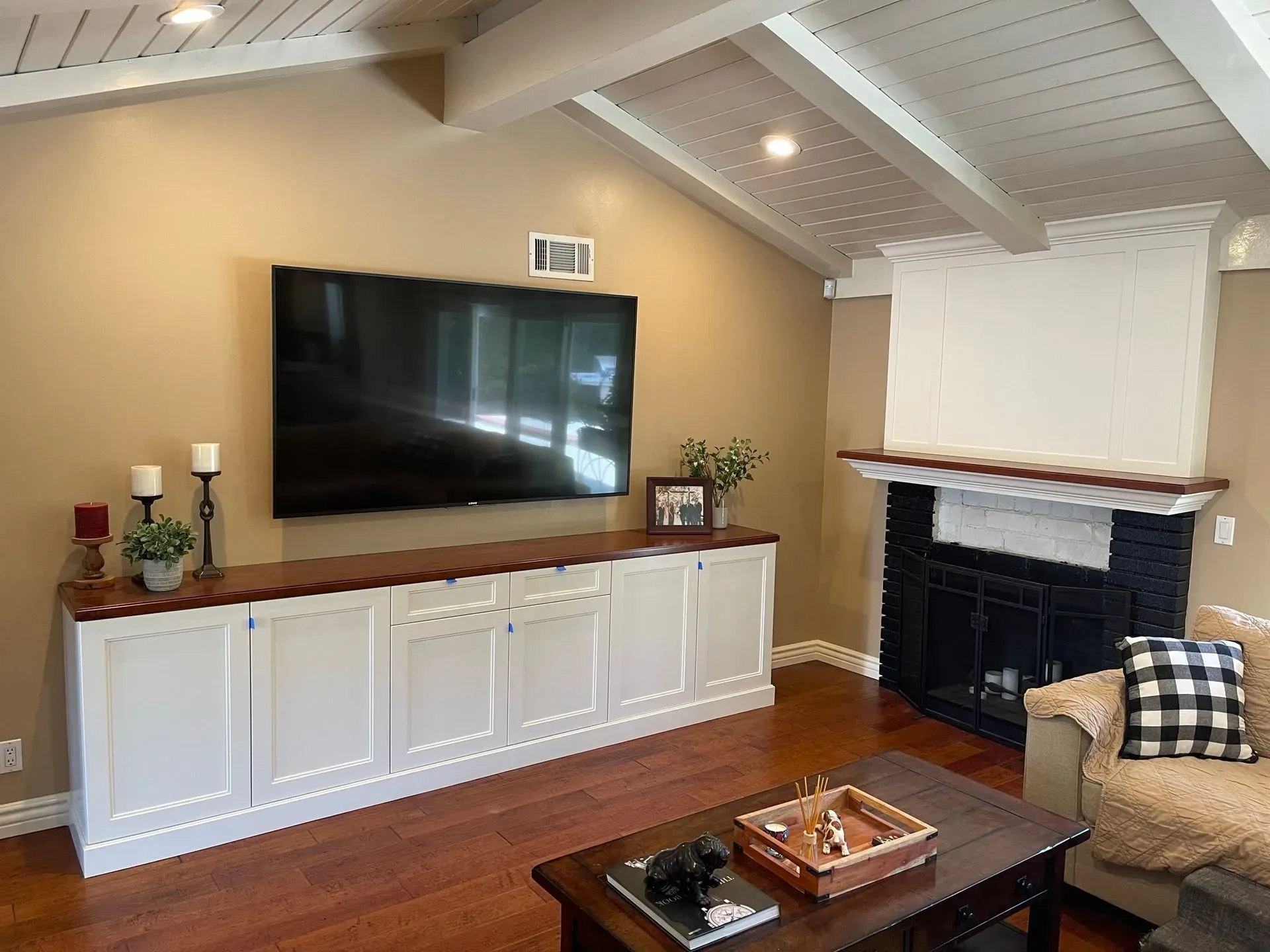 Living room with wall-mounted TV, white cabinets, fireplace, and coffee table on hardwood floor