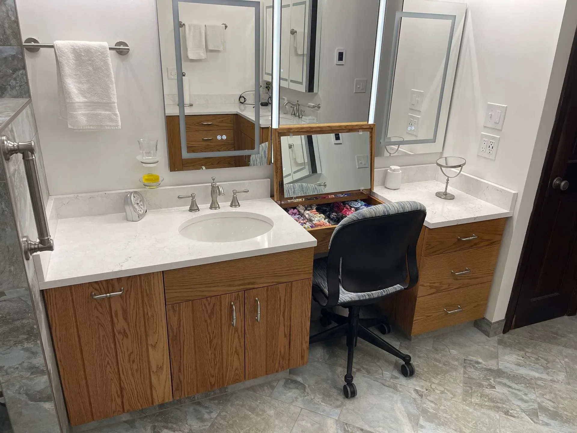 Bathroom vanity with mirror, sink, chair, and grooming items in a tidy interior.