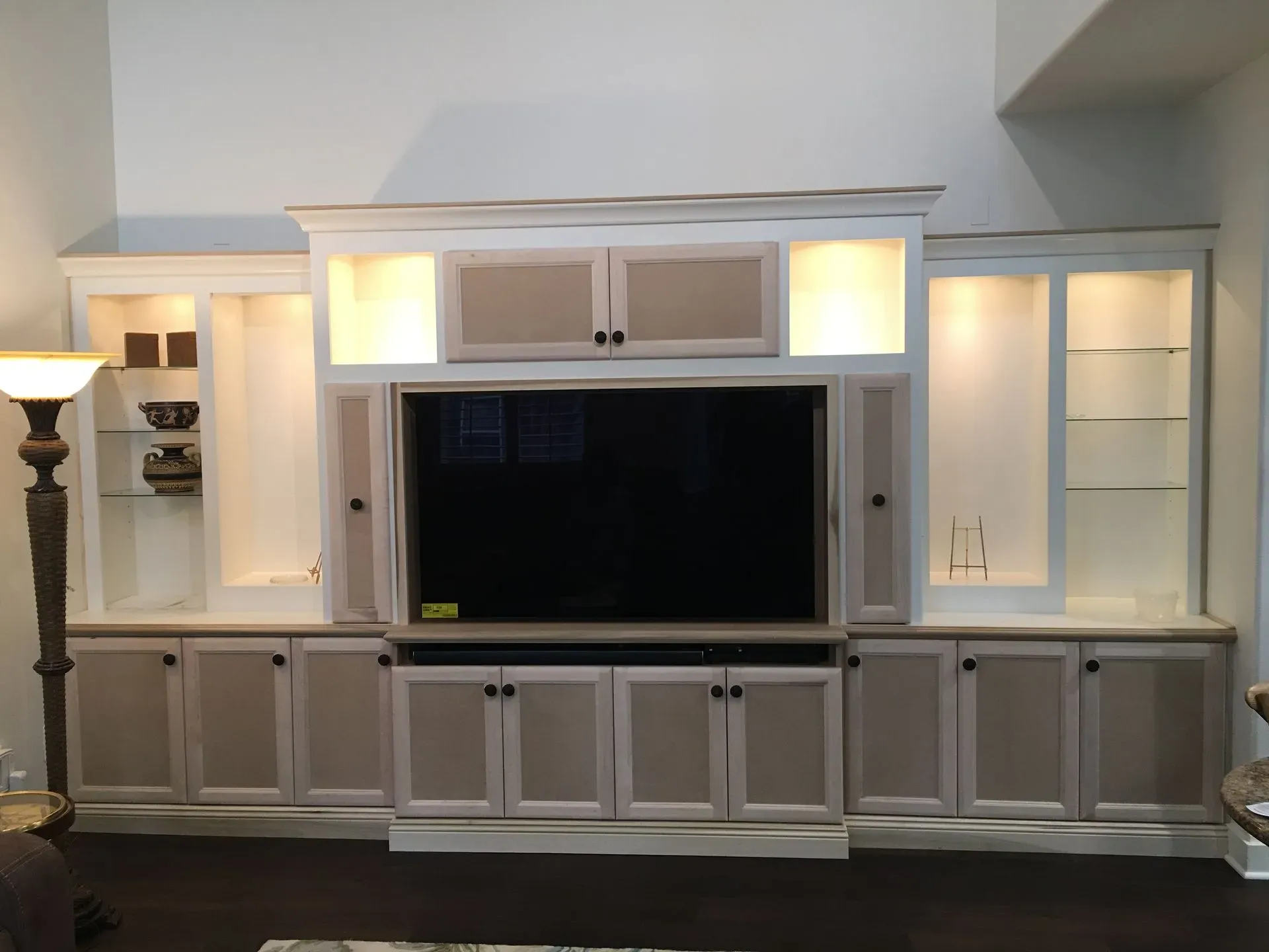 Living room wall unit with built-in shelves, cabinets, and a large flat-screen TV.