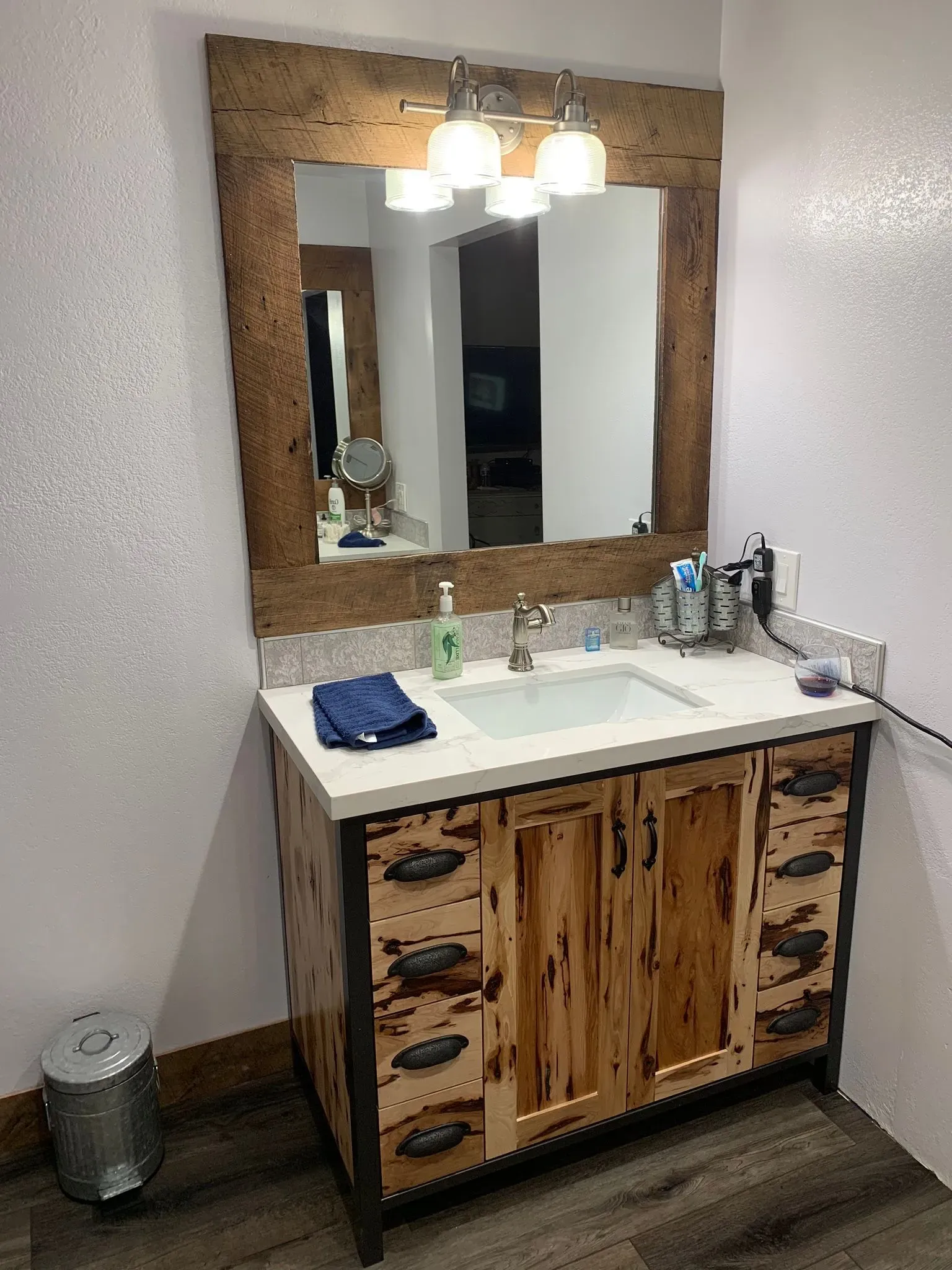 Rustic bathroom vanity with white sink, wood-framed mirror, and overhead lights
