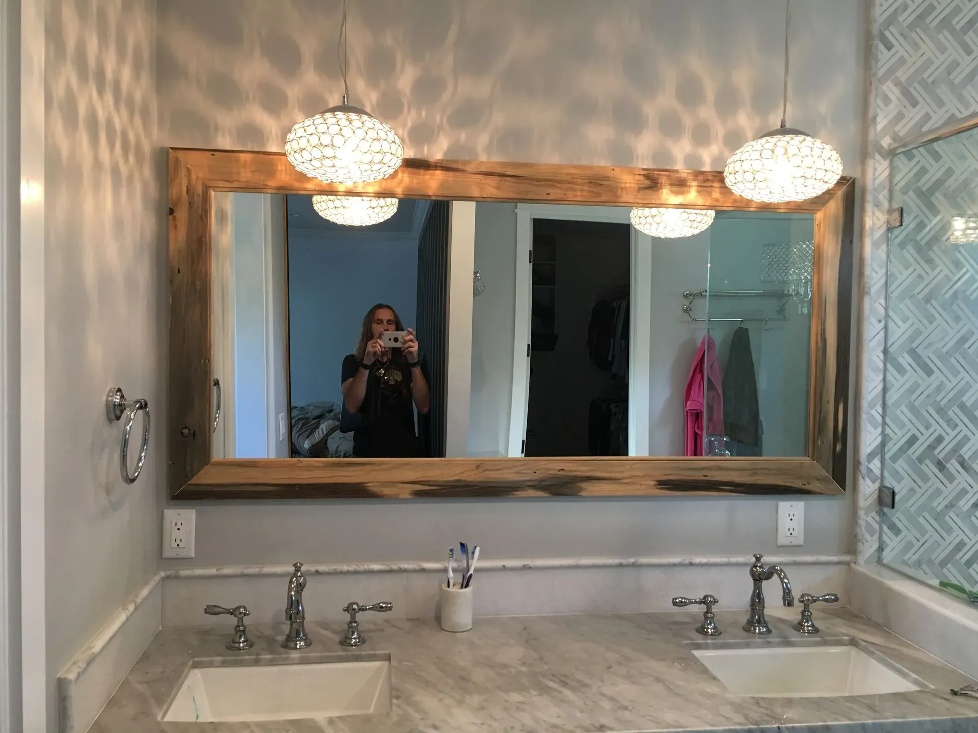 Bathroom vanity with large wooden-framed mirror, two pendant lights, and double sinks.