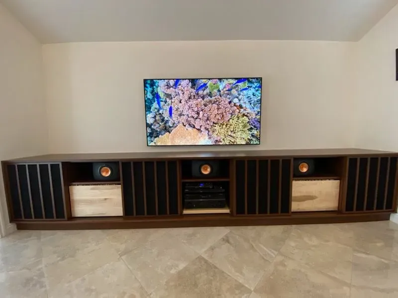 Wall-mounted TV above a long dark wood media console in a minimalist living room with beige tile floor