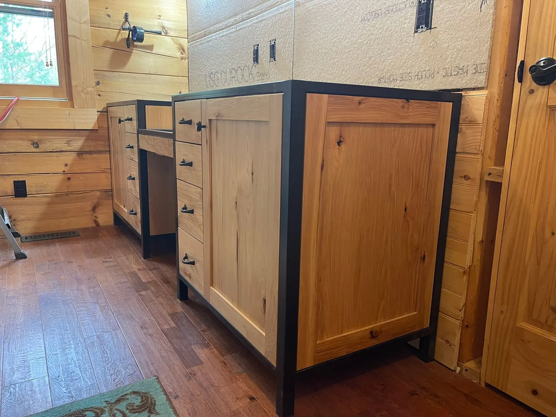 Wood-paneled kitchen with black-framed island cabinets and a window by the sink
