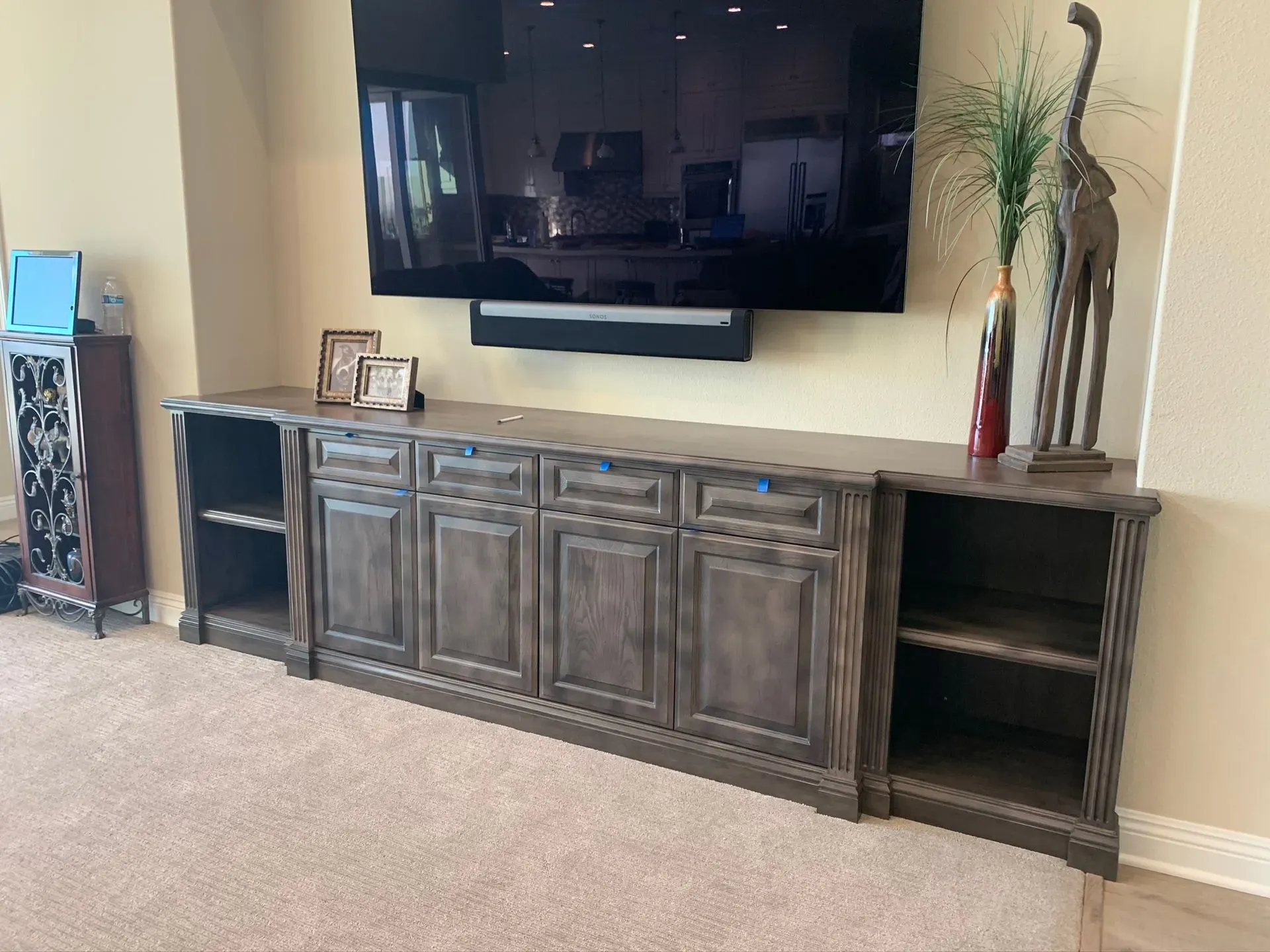Living room with wall-mounted TV above a wooden cabinet and decorative vases on the right.