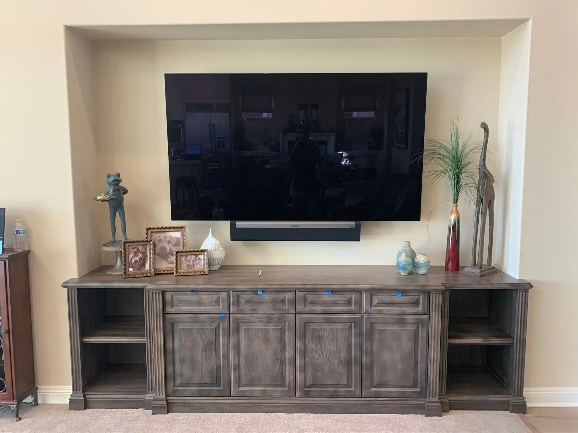 Living room wall with mounted TV above a dark wood console and decorative vases and figurines