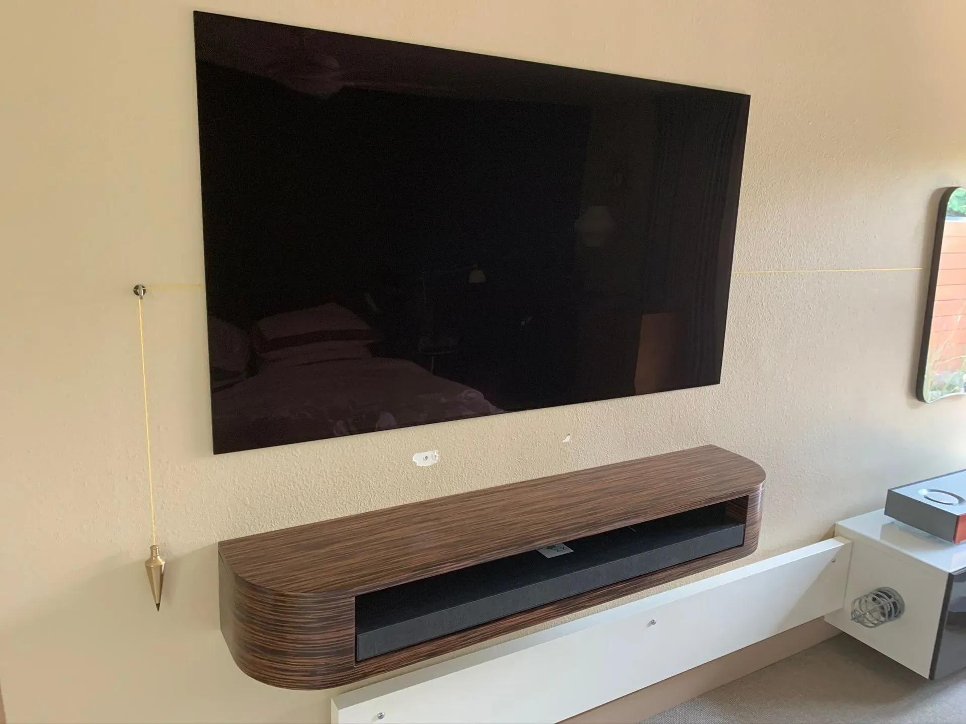 Wall-mounted TV above a floating wooden console in a modern living room