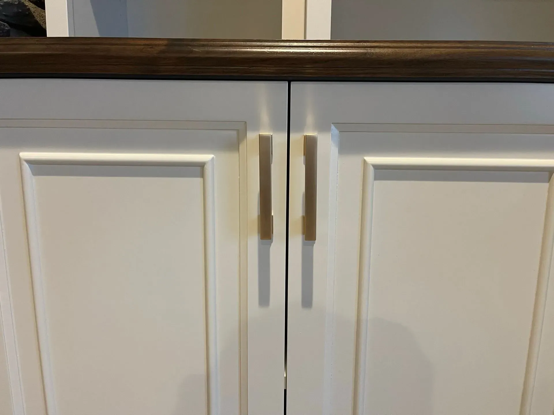 White kitchen cabinet doors with a small gap at the center and a wood countertop above