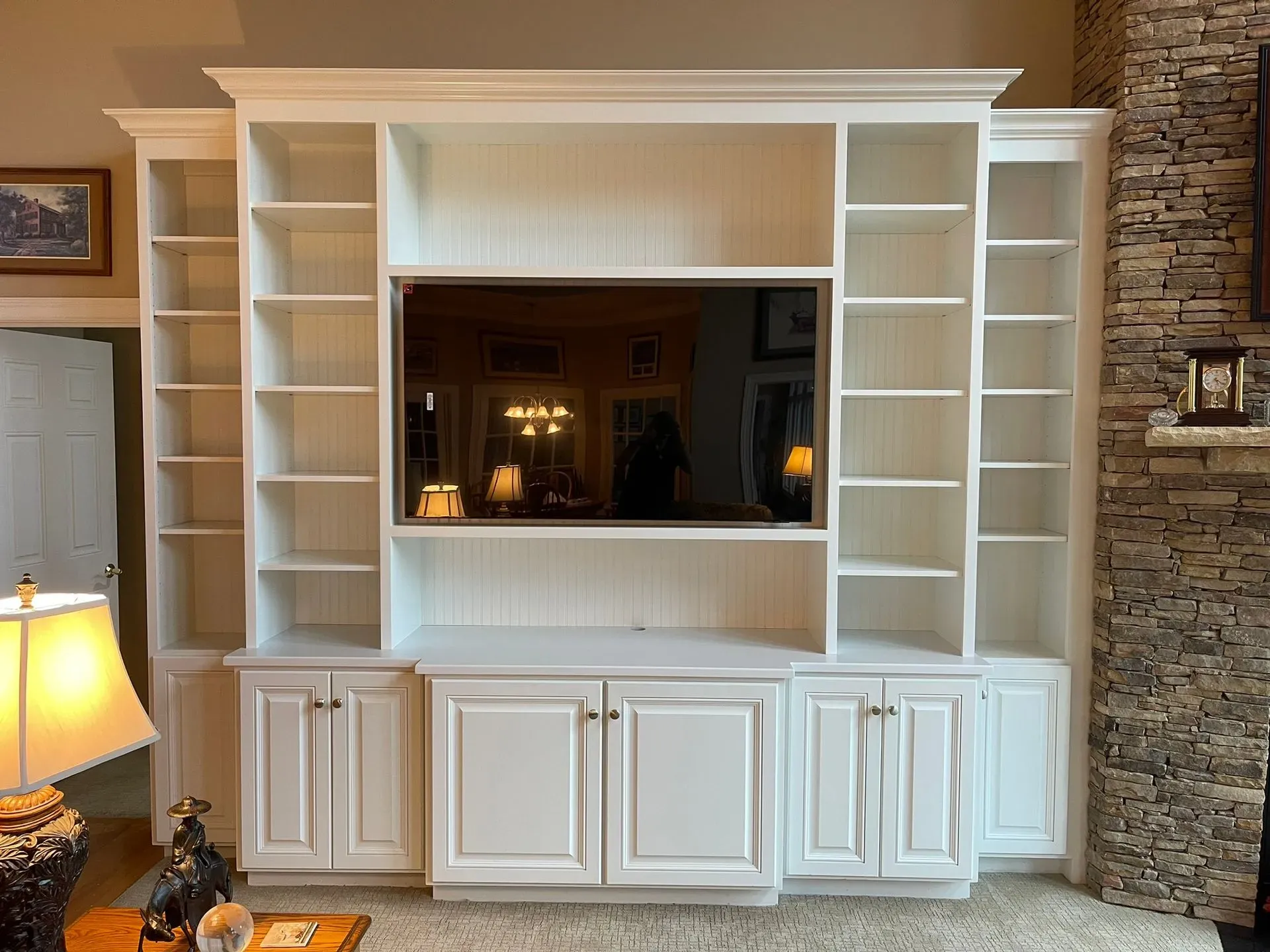 Built-in white wall unit with shelves and cabinets around a central TV niche in a living room